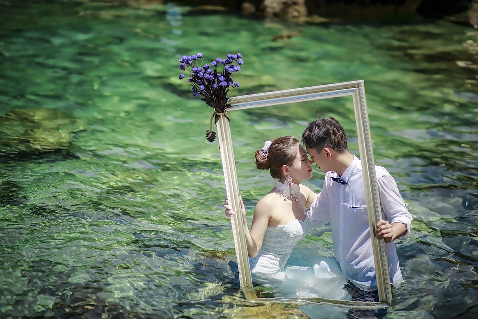 Pareja de recién casados posando con un marco dentro de un estanque. | Foto: Pixabay