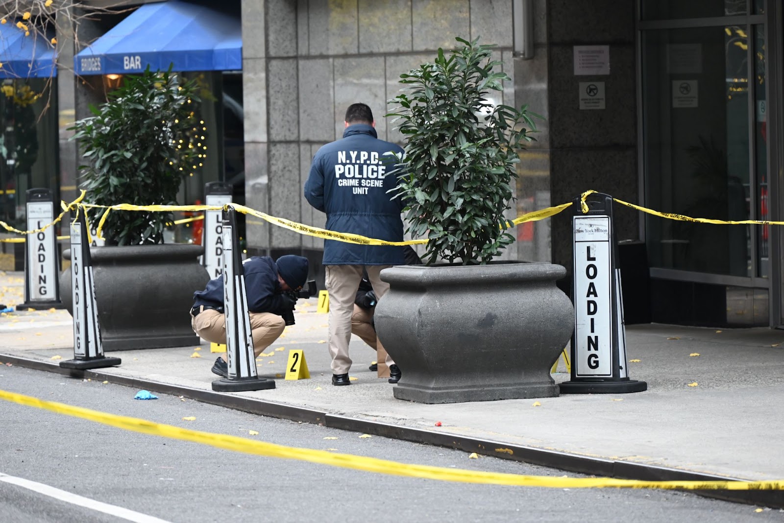 Agentes de policía investigan el lugar donde Brian Thompson, consejero delegado de UnitedHealthcare, recibió un disparo mortal en el centro de Manhattan, cerca de un hotel en la calle 54 entre la 6ª y la 7ª avenidas, el 4 de diciembre de 2024, en Nueva York | Fuente: Getty Images