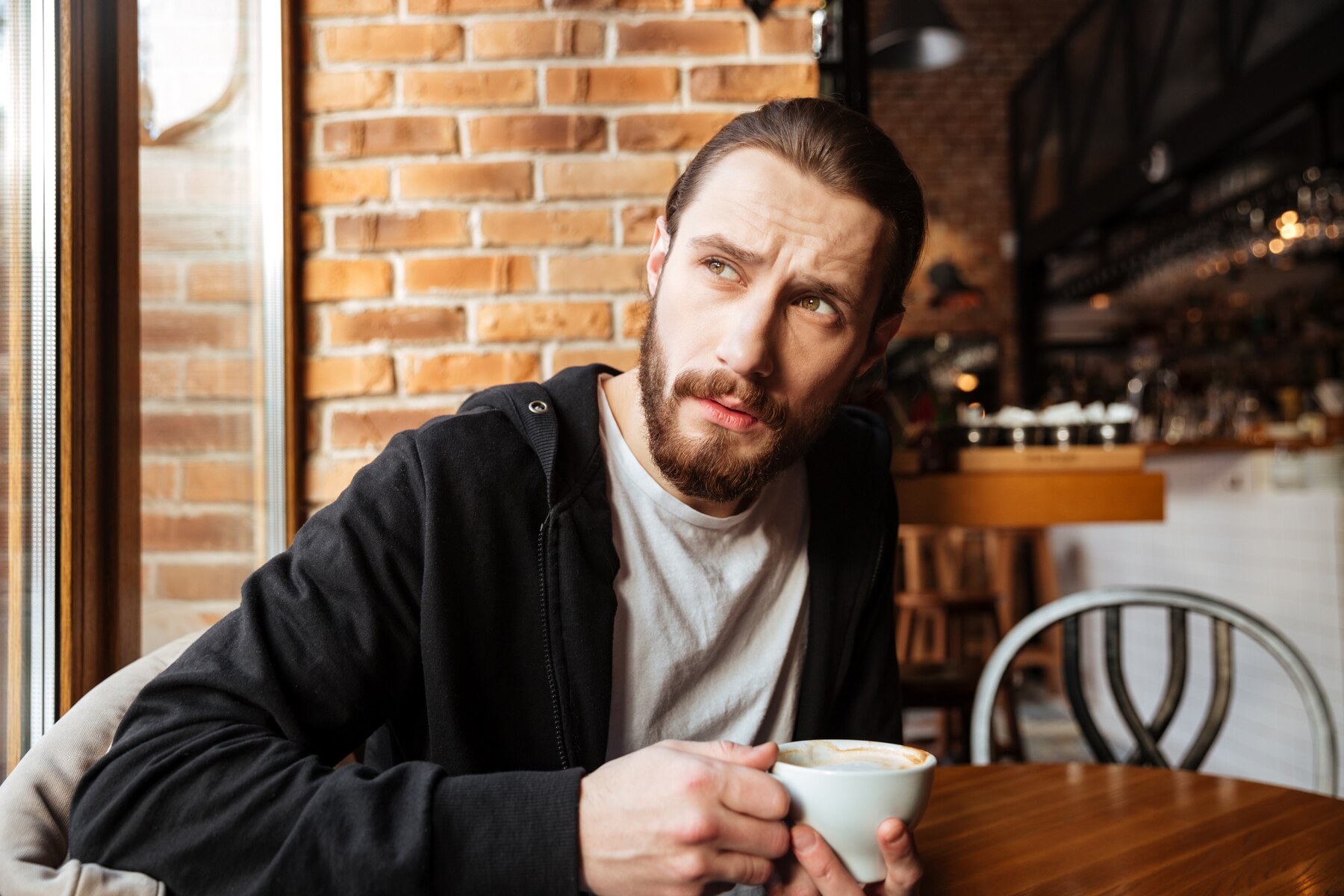 Un hombre pensativo en un café | Fuente: Freepik