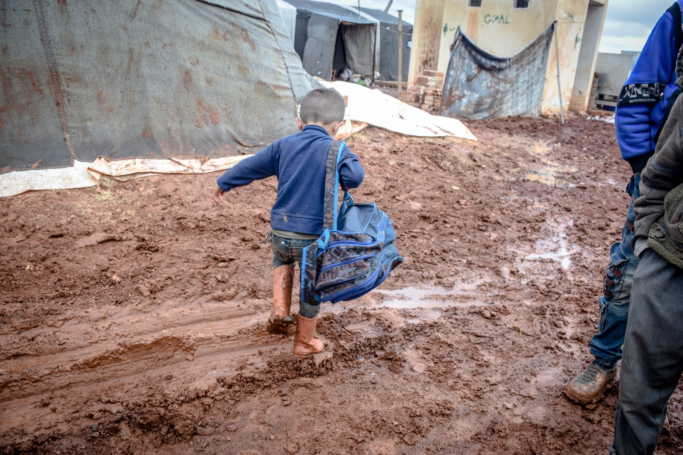 Niño pequeño caminando por un camino de tierra cargando un bolso. | Foto: Pexels