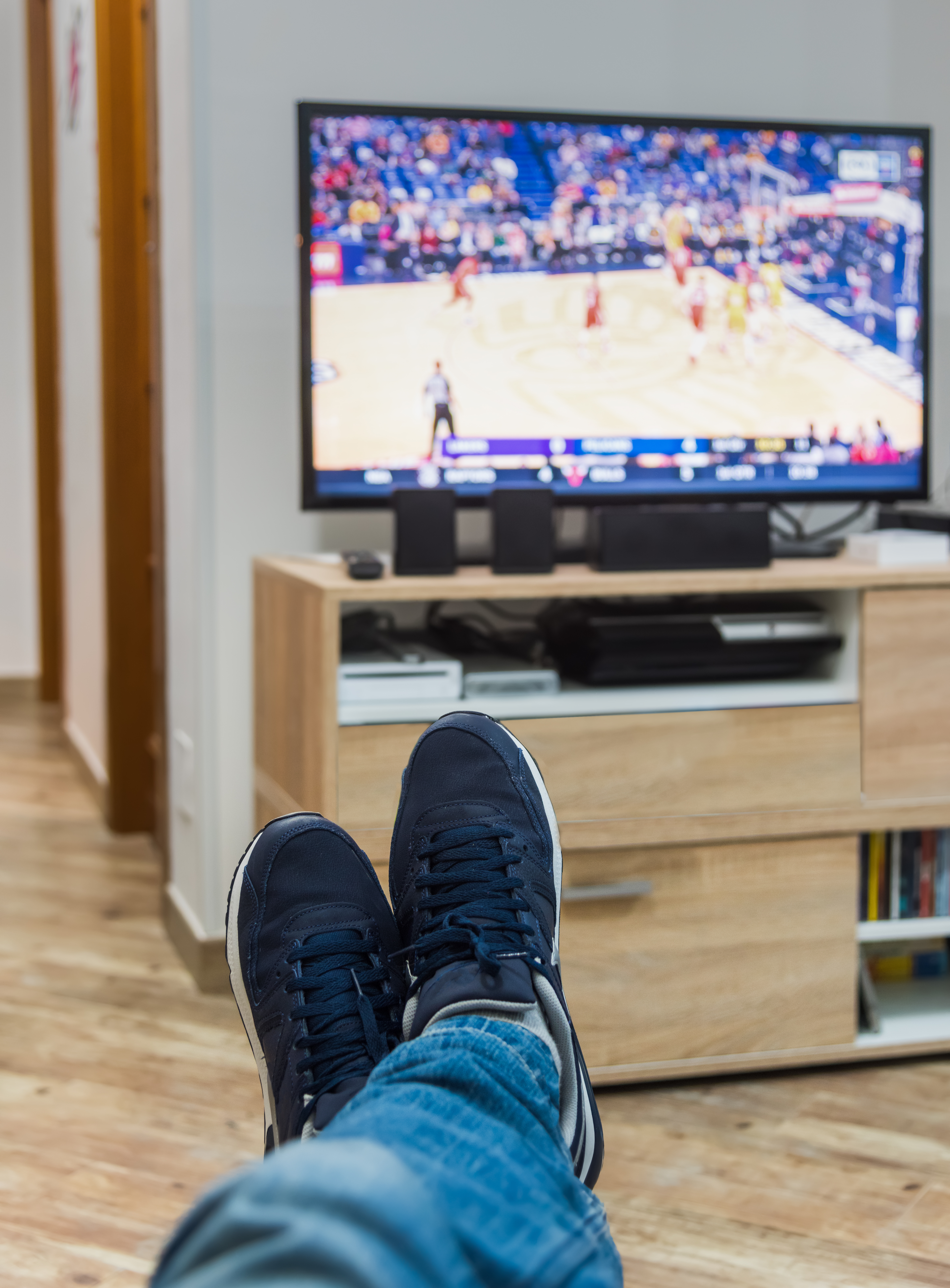 Vista en primera persona de un hombre viendo un partido de baloncesto por televisión. | Fuente: Shutterstock