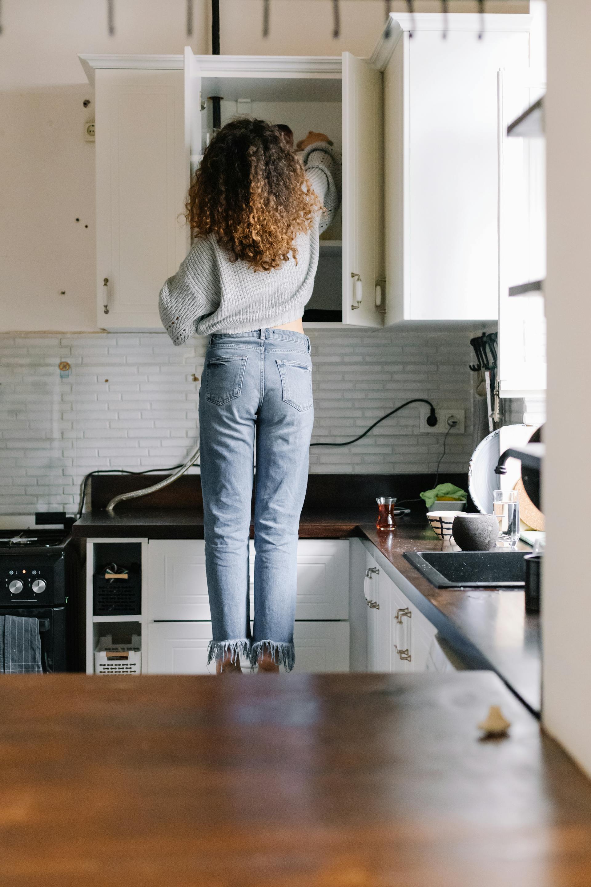 Vista trasera de una mujer abriendo un armario de cocina | Fuente: Pexels