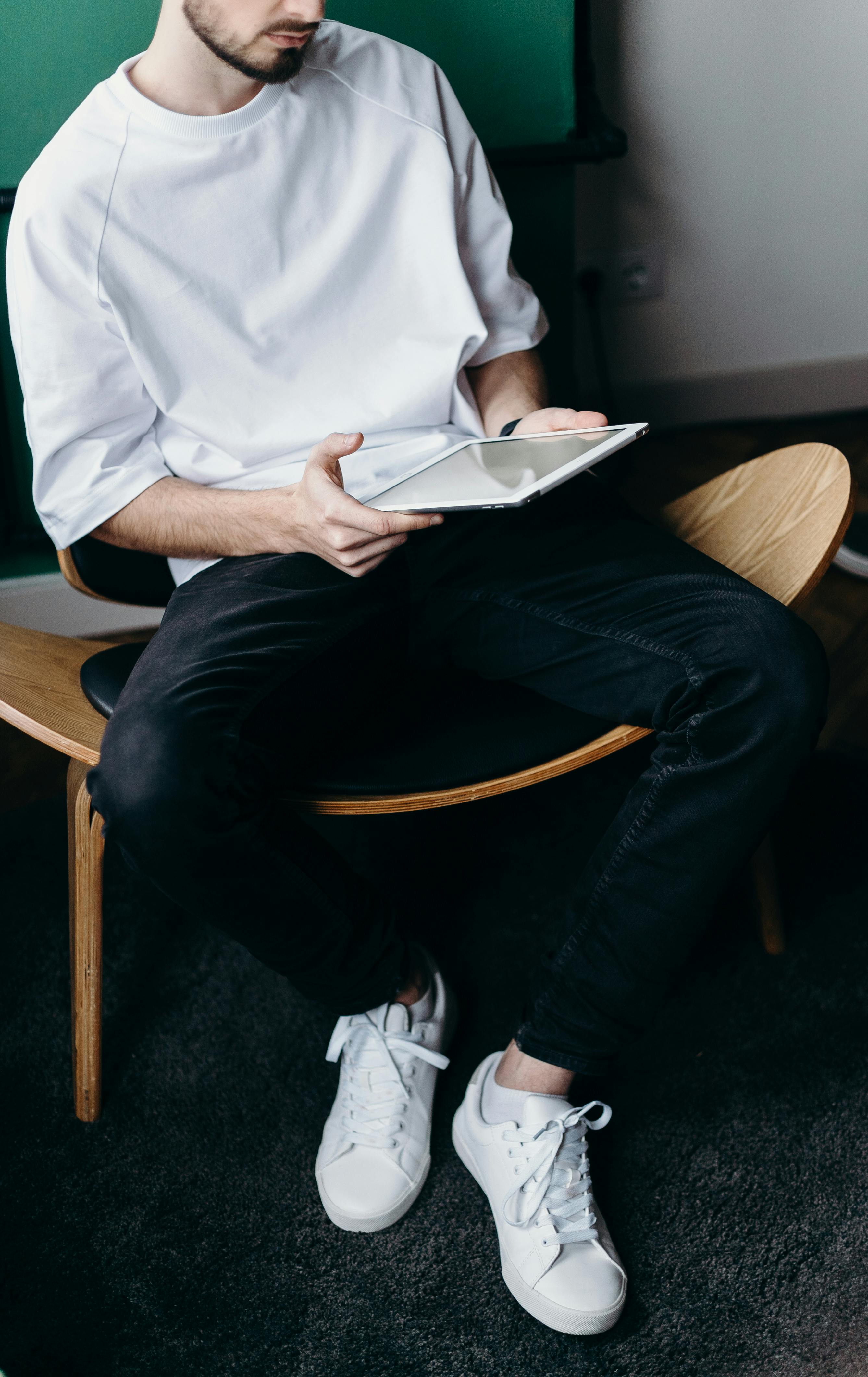 Hombre con camisa blanca y pantalones negros usando una tableta | Fuente: Pexels