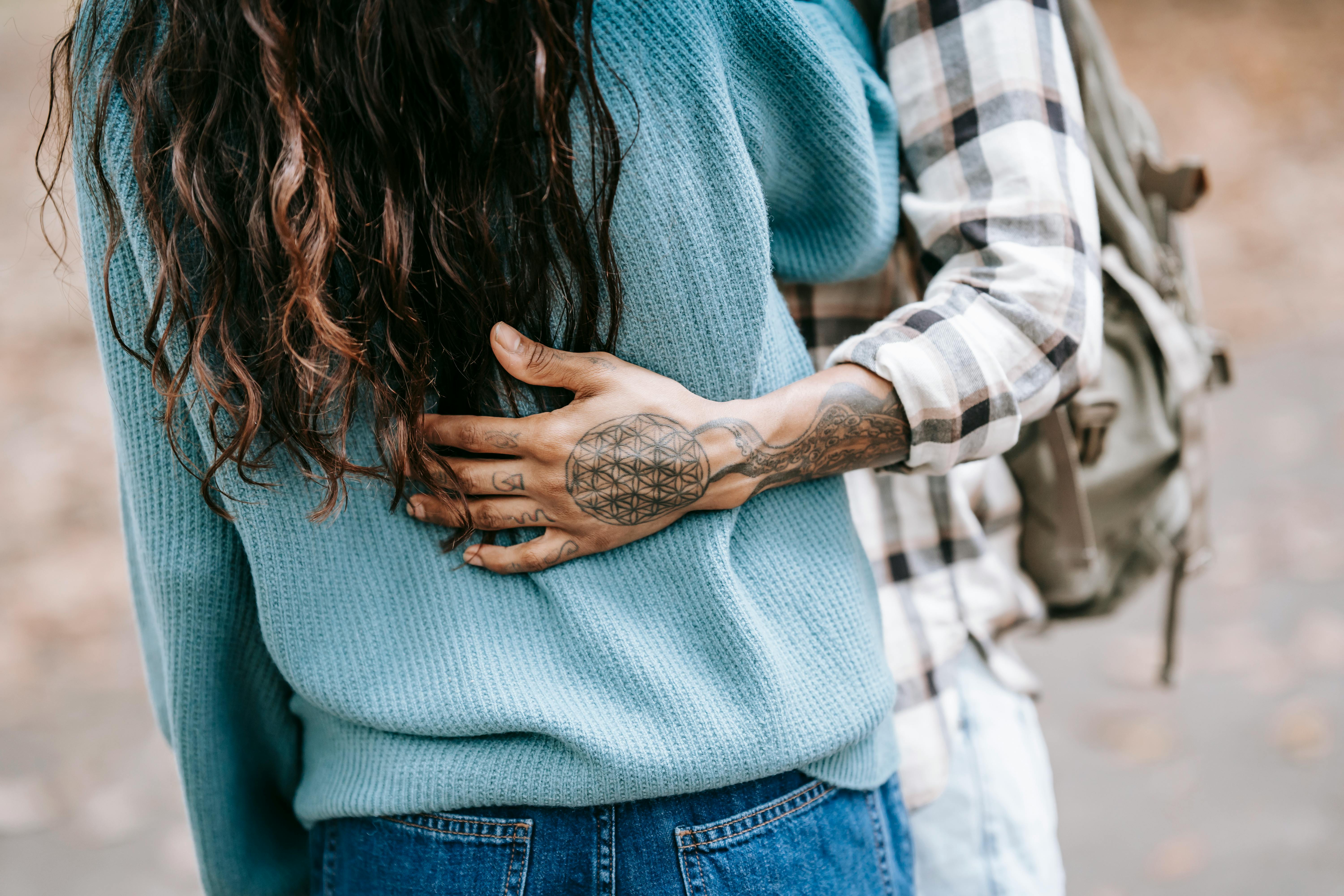 Un hombre con tatuajes abrazando suavemente a su novia | Fuente: Pexels
