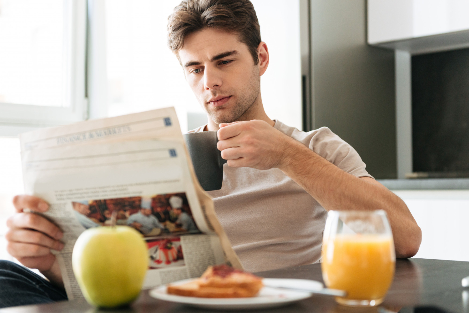 Hombre en la cocina con su café y su periódico | Fuente: Freepik