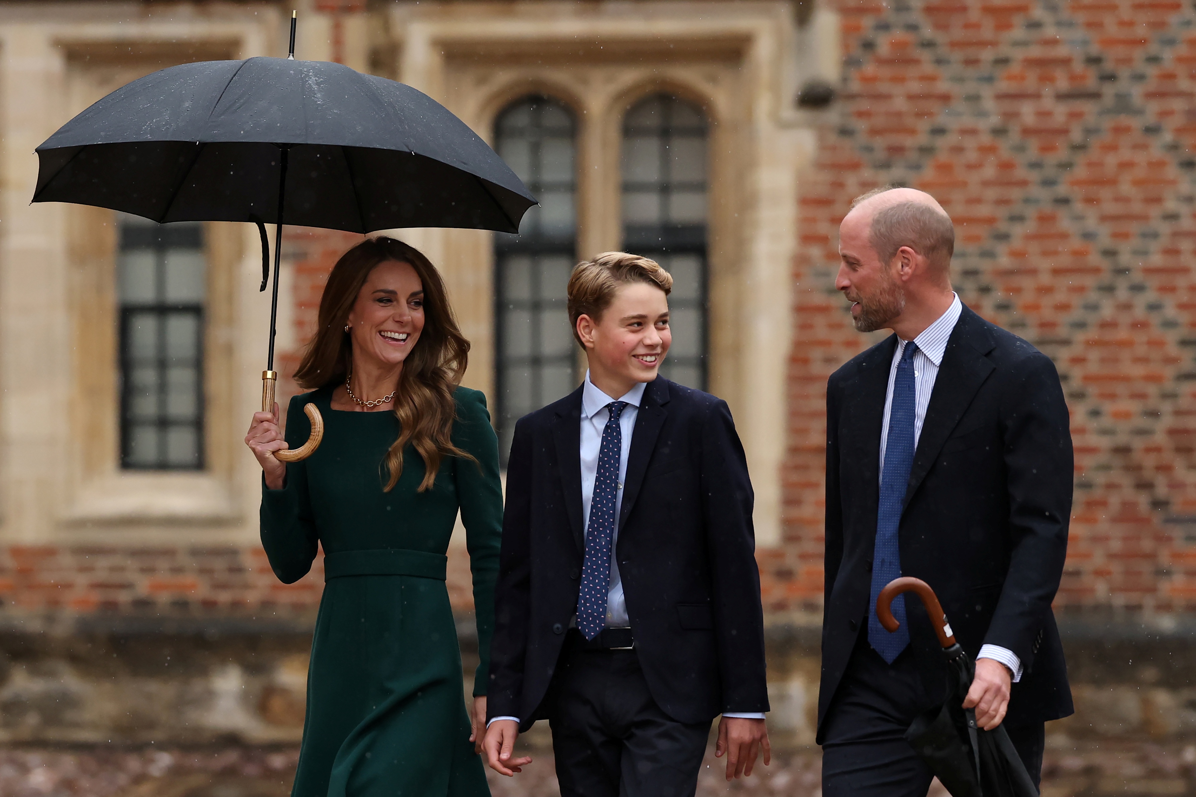 George se volvió hacia William en un momento de distensión, mientras Catherine caminaba a su lado bajo un paraguas. La llegada de la familia reflejó cómo los padres acompañaban a su hijo mayor en su nueva etapa educativa.