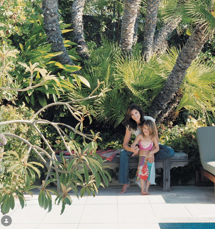 Cindy está sentada junto a la pequeña Kaia al lado de la piscina de la casa familiar en Malibú. Cindy dijo que los espacios al aire libre se convirtieron en parte de la vida cotidiana de la familia mientras los niños crecían. | Fuente: Instagram/elledecor