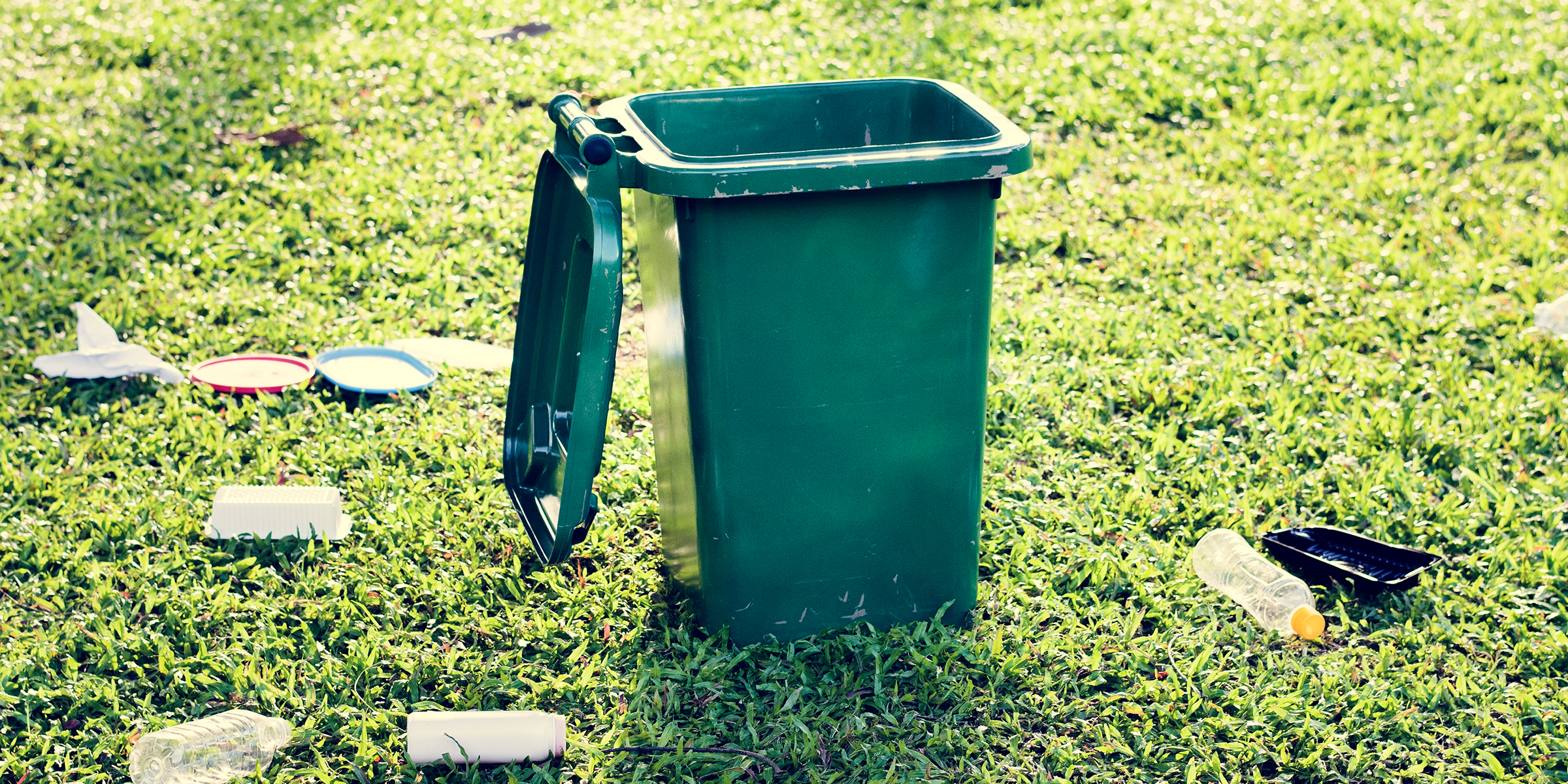 Una papelera y basura sobre el césped | Fuente: Shutterstock