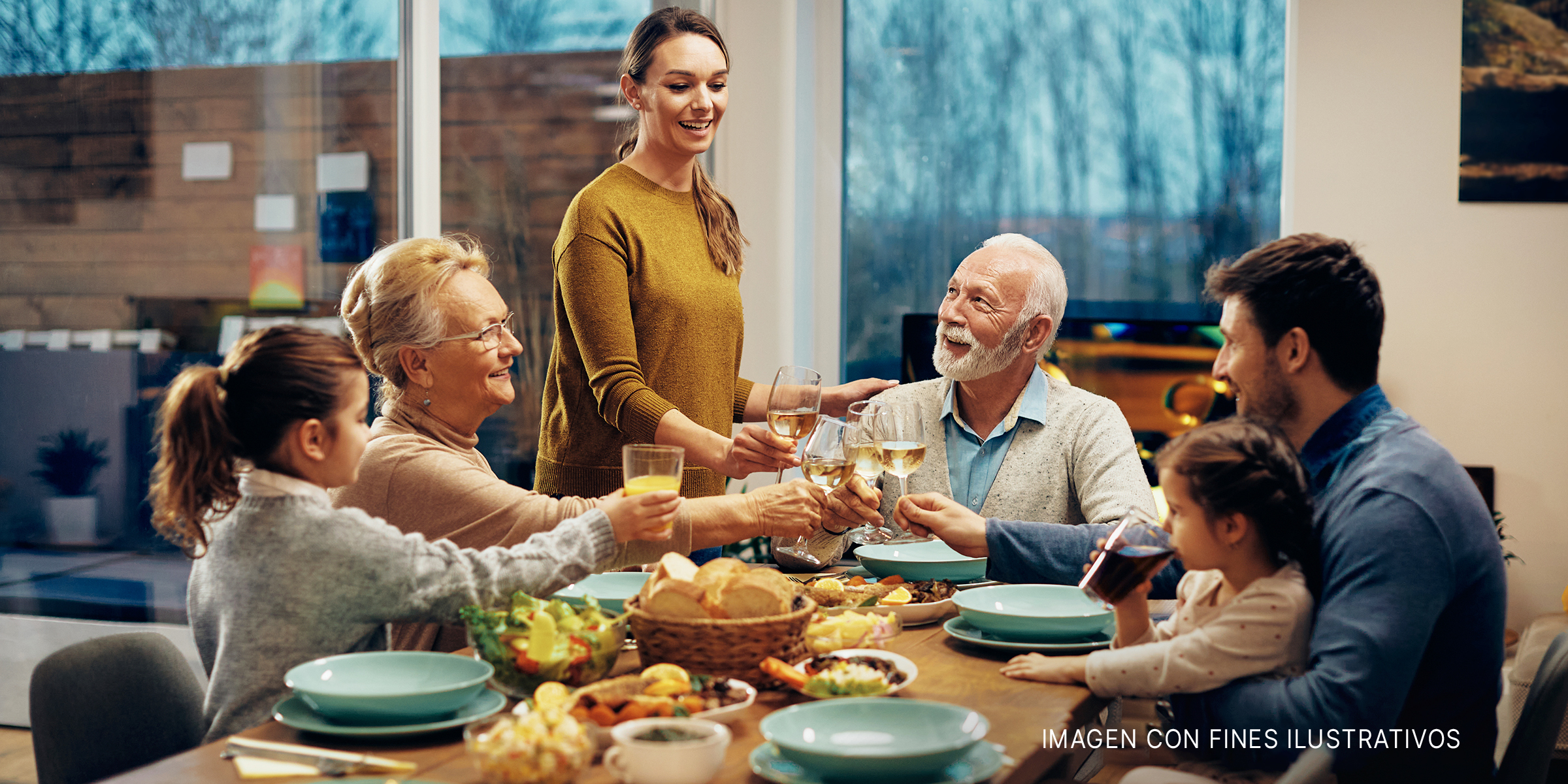 Una feliz familia extendida brindando mientras almuerzan juntos en un comedor. | Foto: Shutterstock