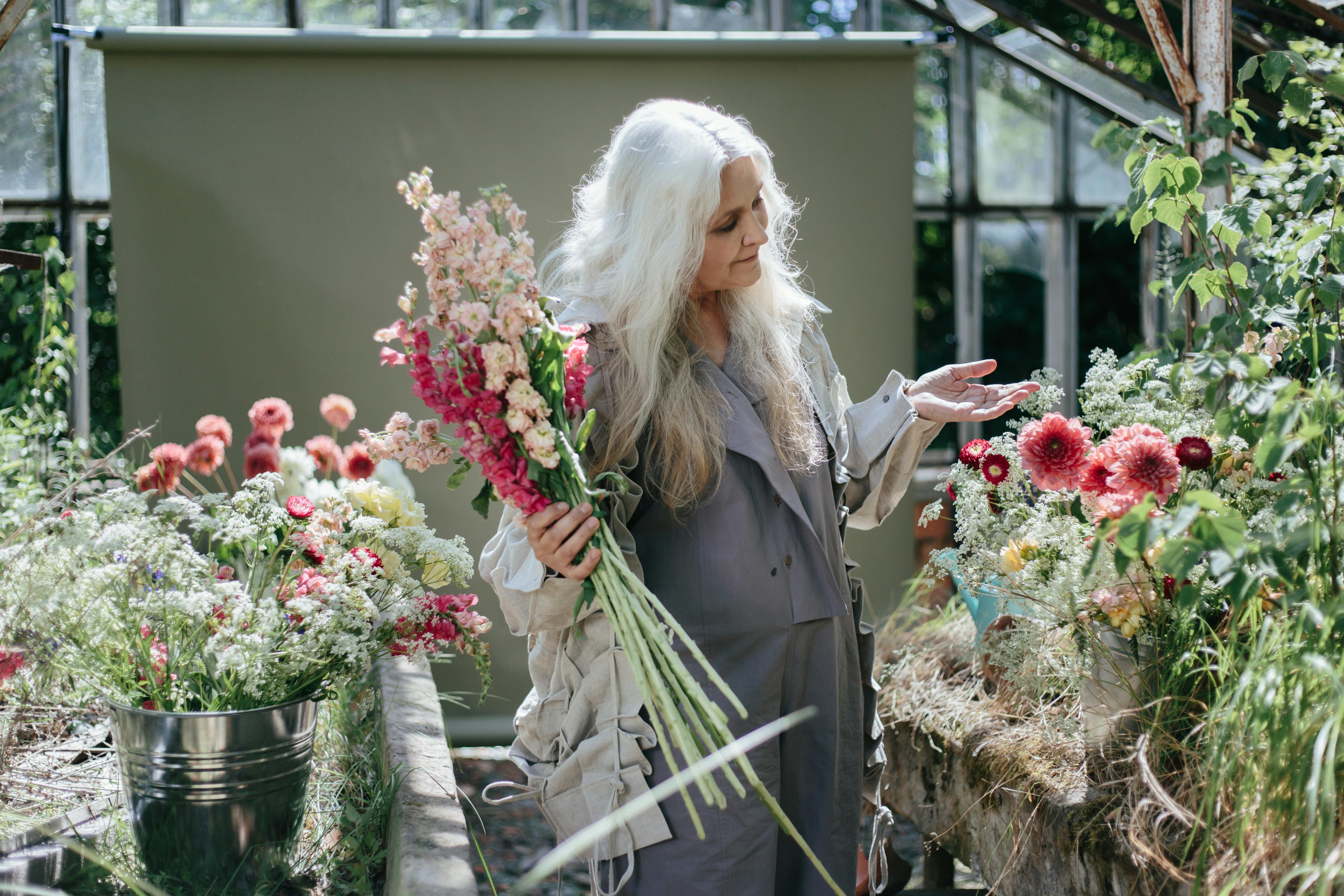 Una anciana rodeada de flores | Fuente: Pexels