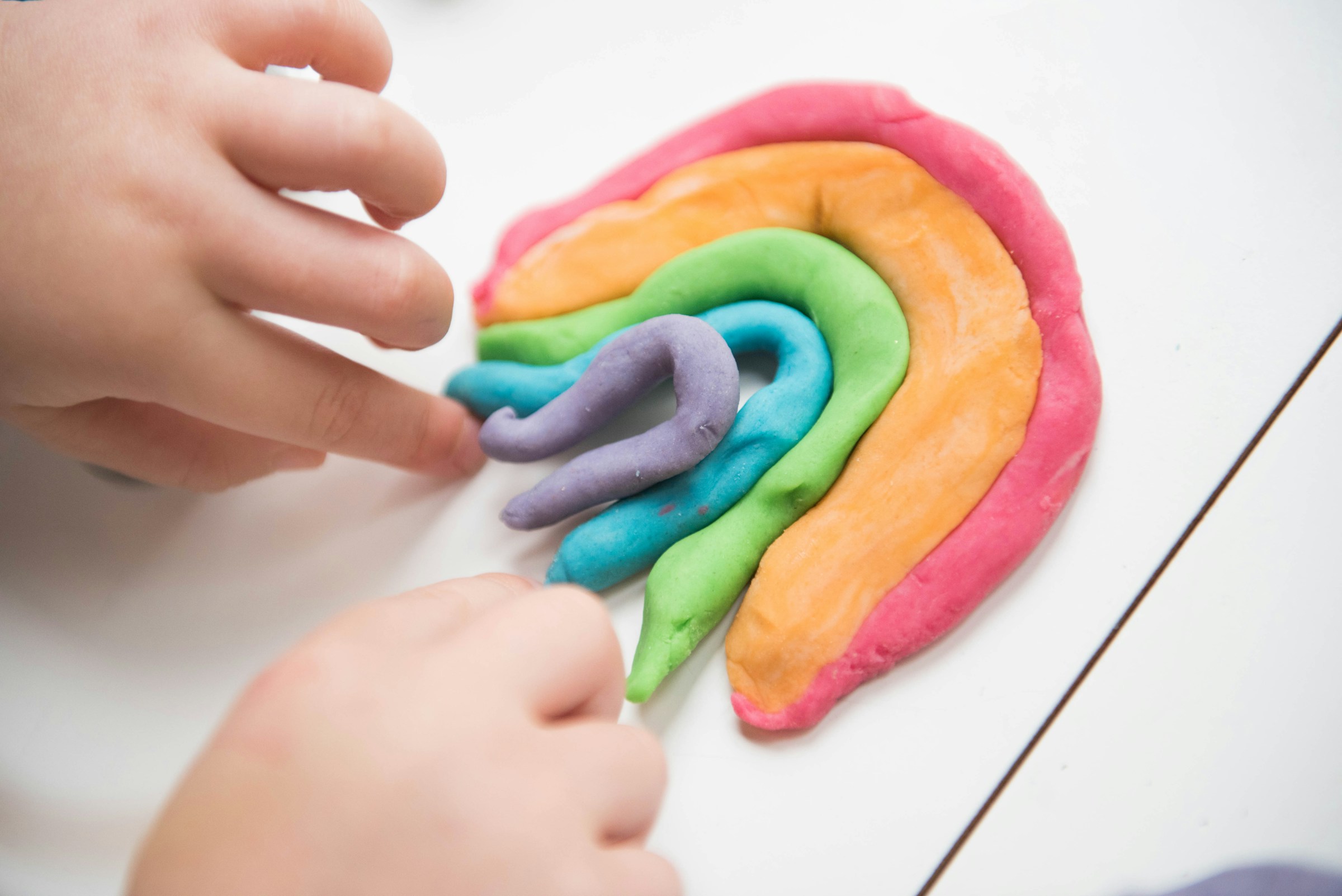 Primo piano di un bambino che gioca con strisce colorate di Play-Doh | Fonte: Unsplash