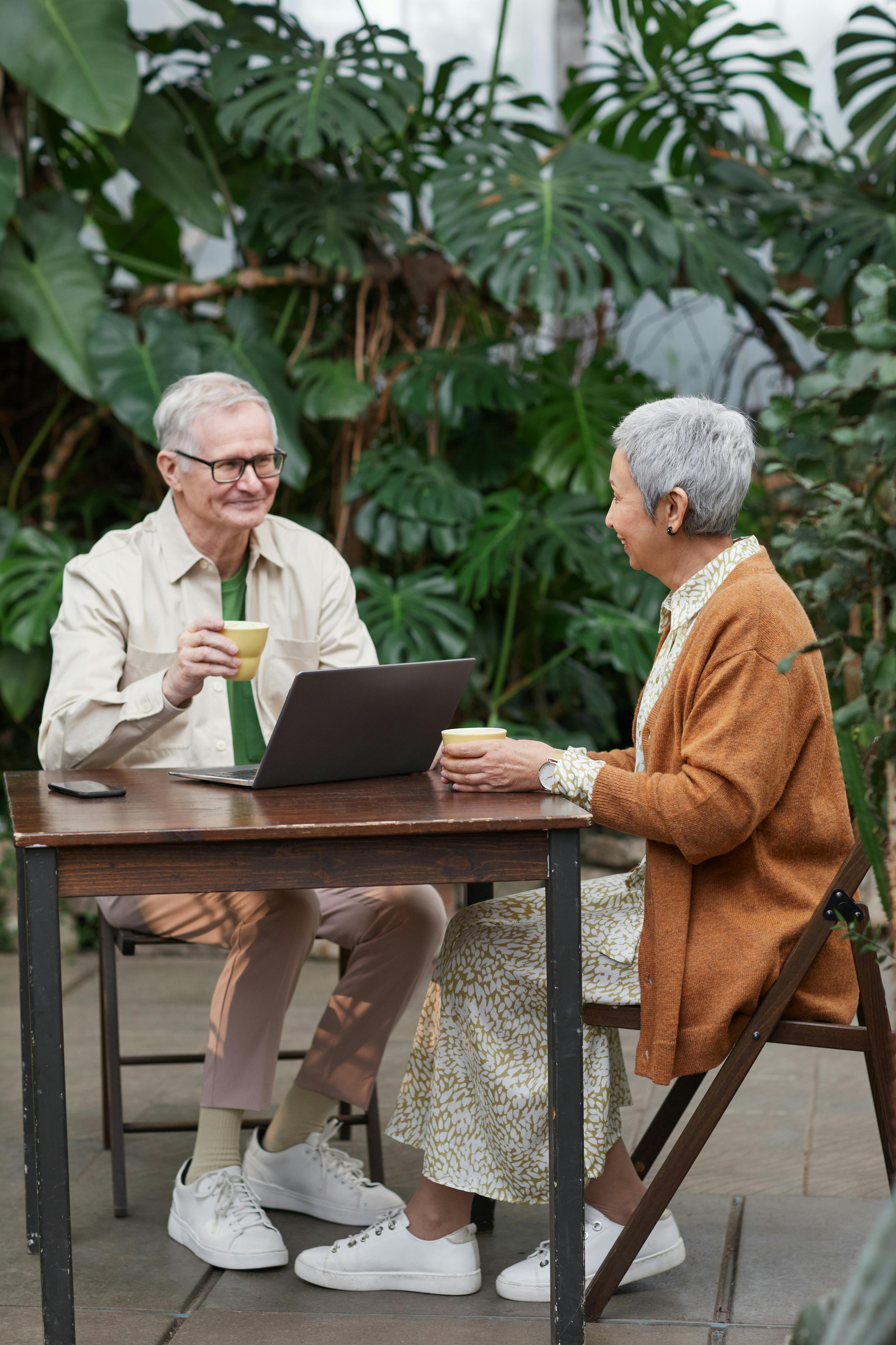 Una pareja flirtea y sonríe mientras disfruta de unas bebidas con un portátil a la vista | Foto: Pexels