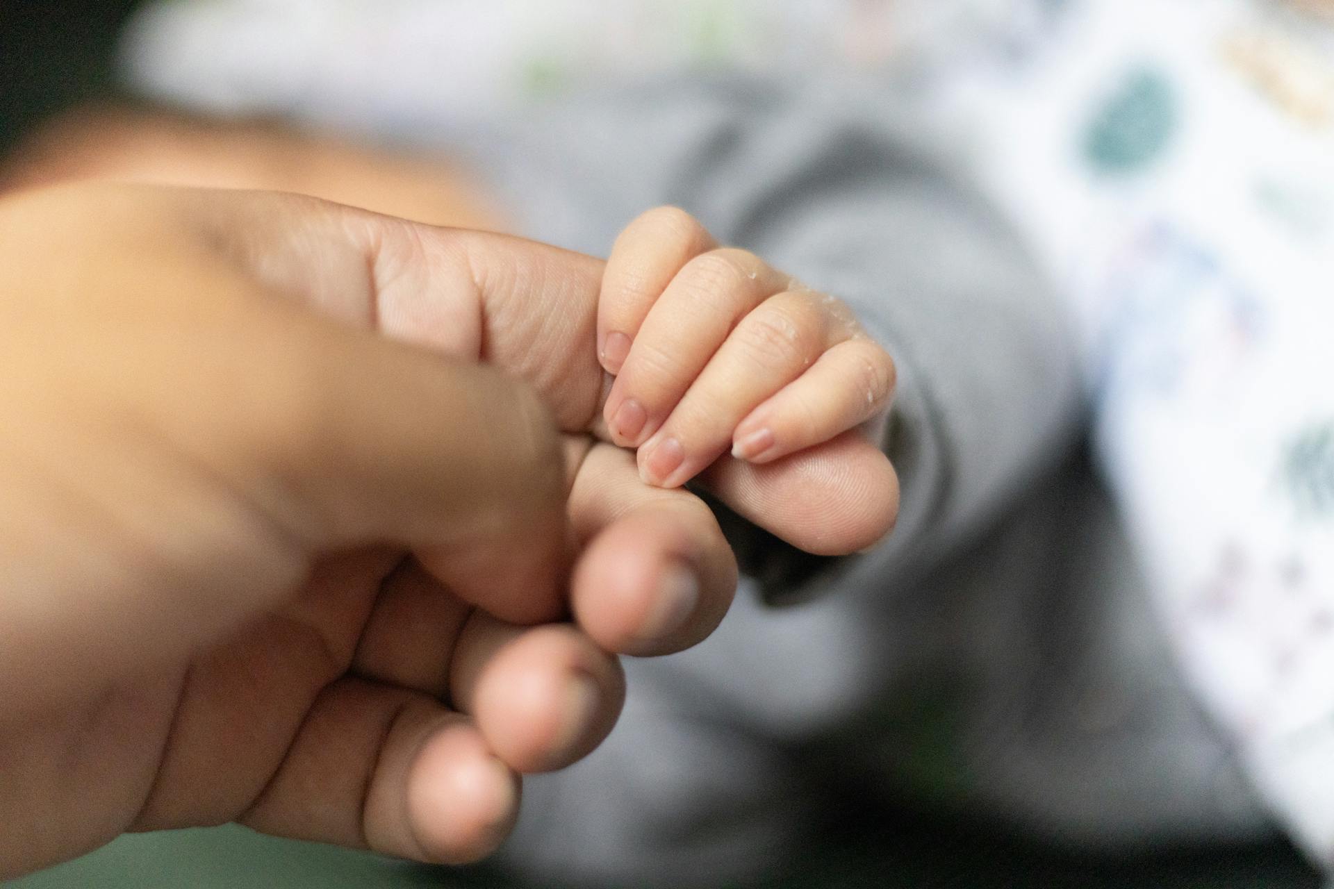 Un bebé sujetando el dedo de un hombre | Fuente: Pexels