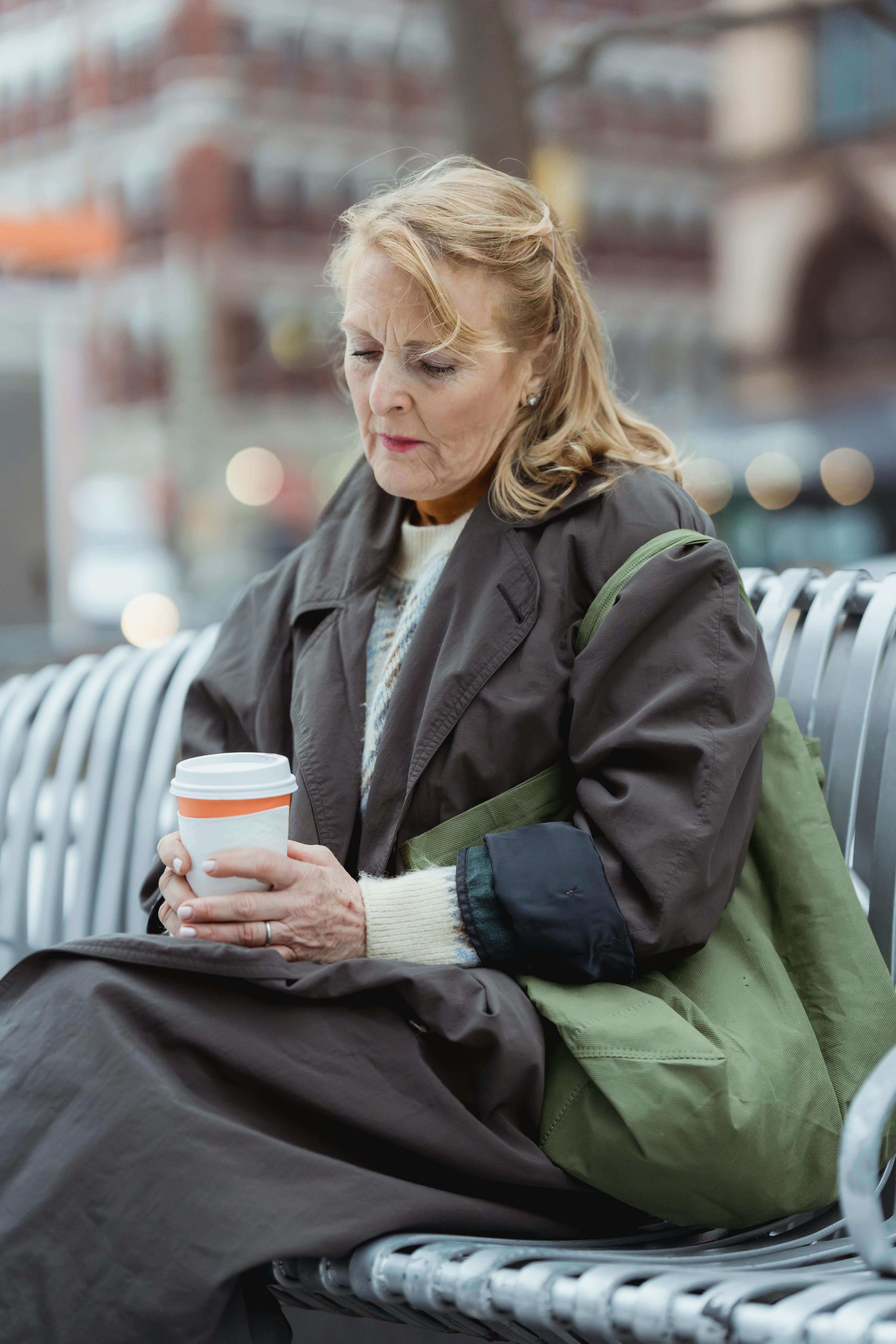 Mujer sostiene una bebida sentada en un banco al aire libre | Foto: Pexels