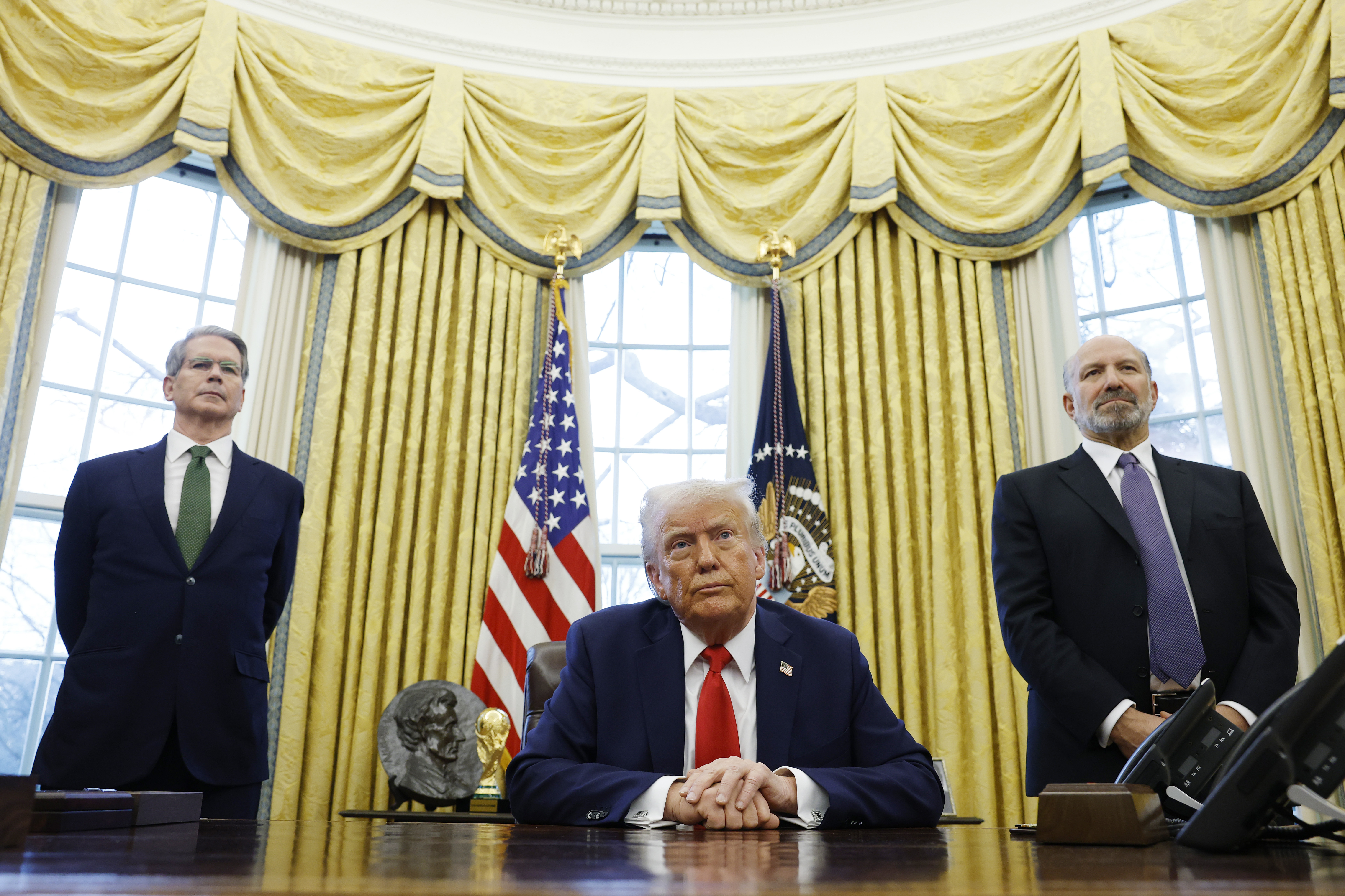 El secretario del Tesoro de EEUU, Scott Bessent, y Howard Lutnick, candidato a secretario de Comercio del presidente de EEUU, Donald Trump, se sitúan detrás de Donald Trump mientras habla con los periodistas. | Fuente: Getty Images