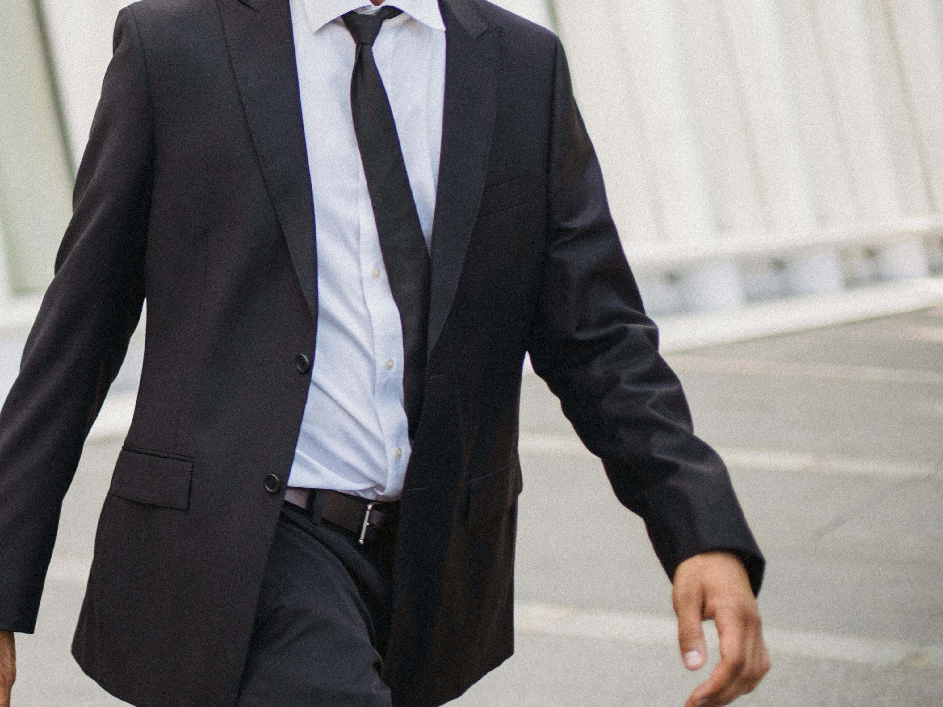 Un hombre con traje y corbata, caminando apresuradamente | Fuente: Pexels