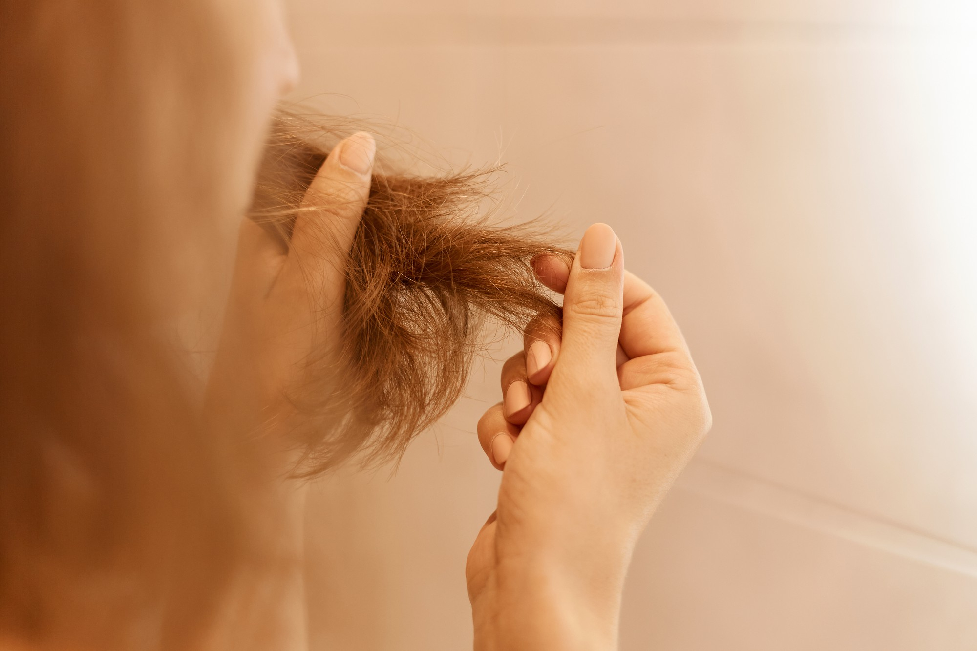 Una mujer mirándose el cabello | Fuente: Freepik