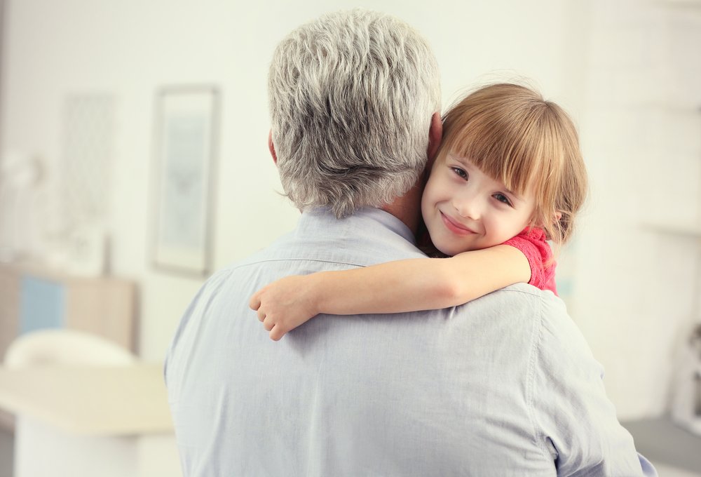 Niña abrazando a su abuelo en casa. | Fuente: Shutterstock