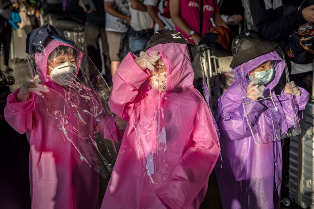 Niños con impermeables, cubiertas de plástico, guantes, gafas y máscaras faciales mientras esperan su vuelo en el Aeropuerto Internacional Ninoy Aquino el 18 de marzo de 2020 en Manila, Filipinas. | Foto por Ezra Acayan vía Getty Images
