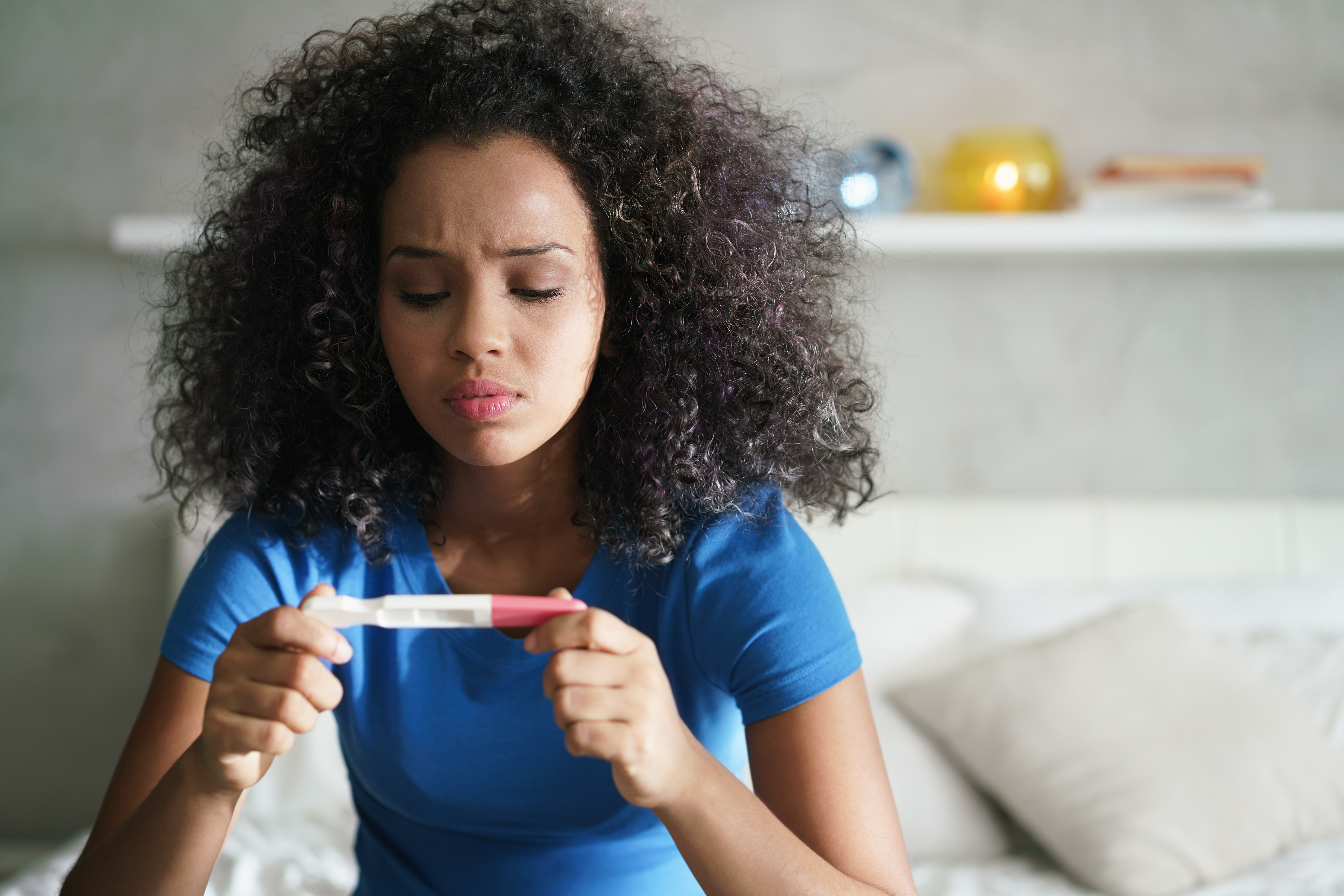 Chica con prueba de embarazo en su habitación | Fuente: Shutterstock.com