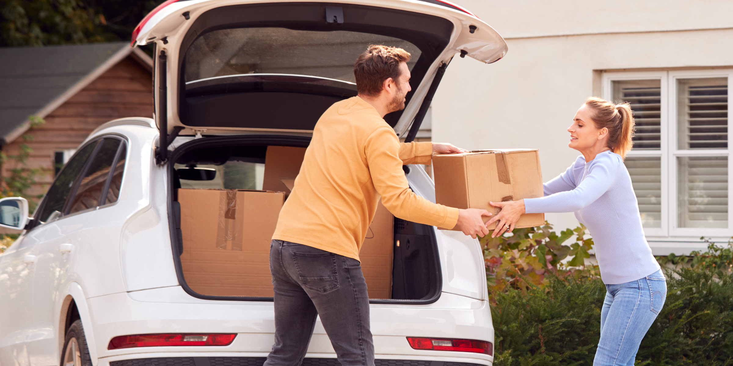 Hombre y mujer cargando cajas en un automóvil | Fuente: Shutterstock