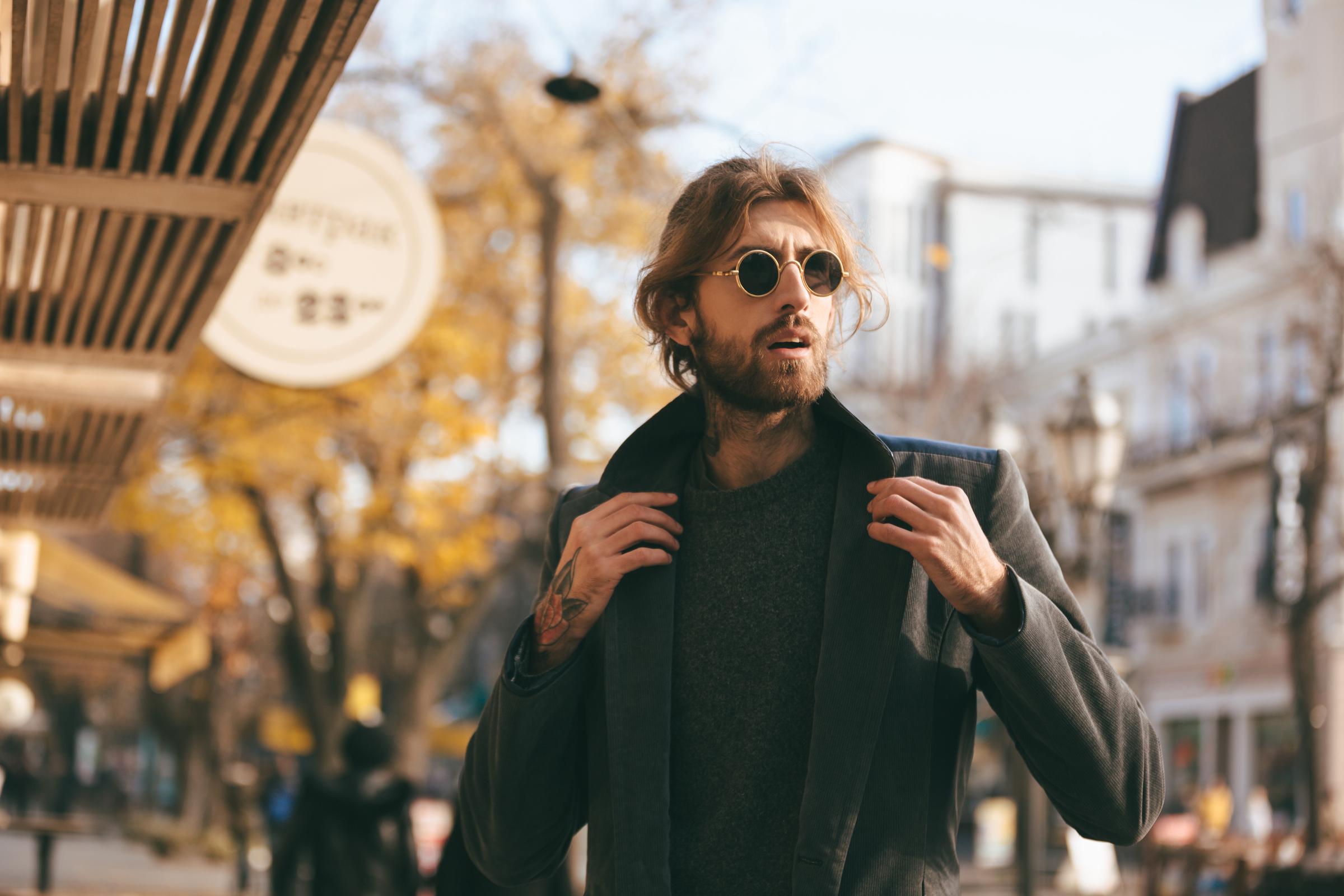 Un hombre guapo con gafas de sol y abrigo | Fuente: Freepik