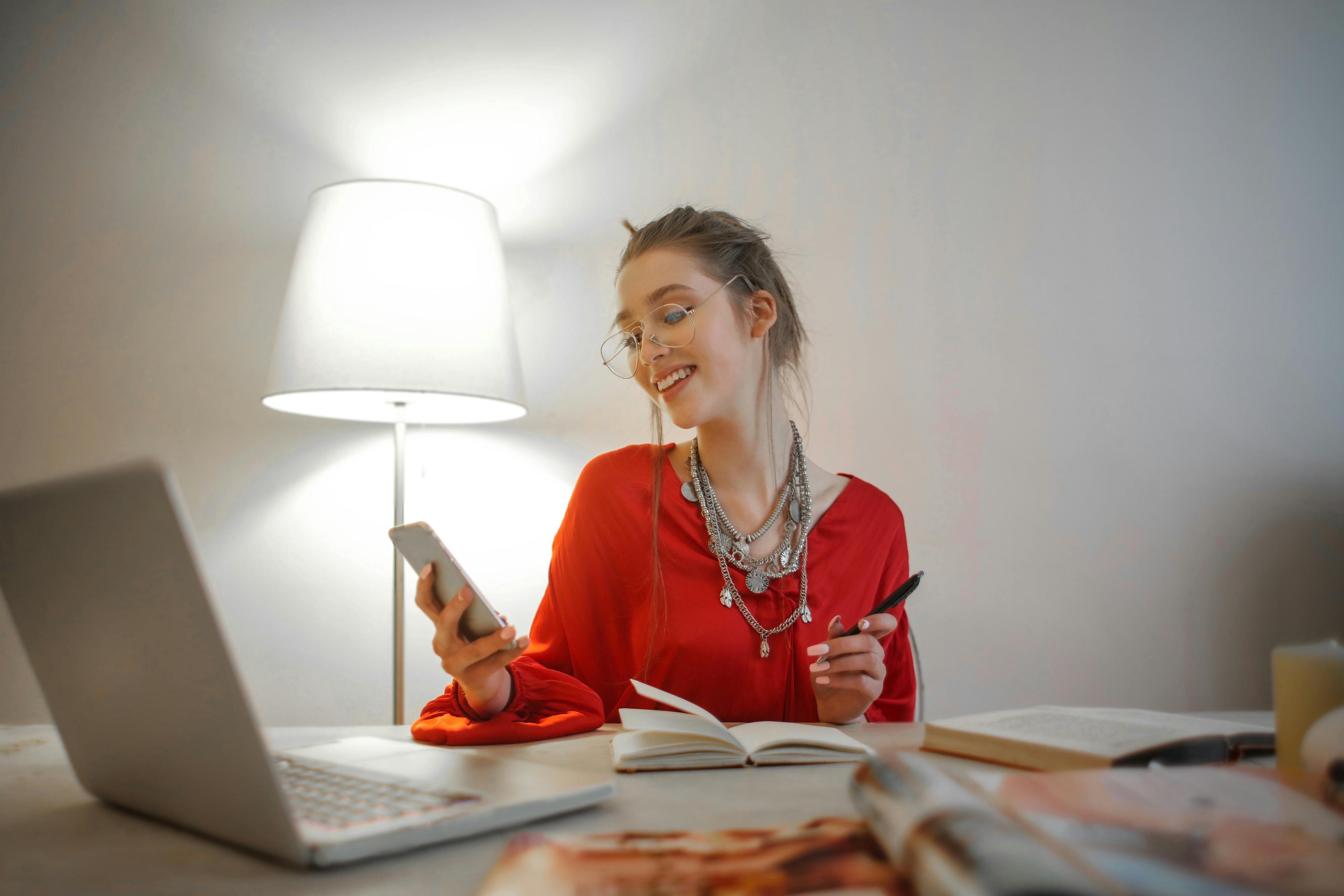 Una mujer sonriendo mientras sostiene un teléfono móvil | Fuente: Pexels