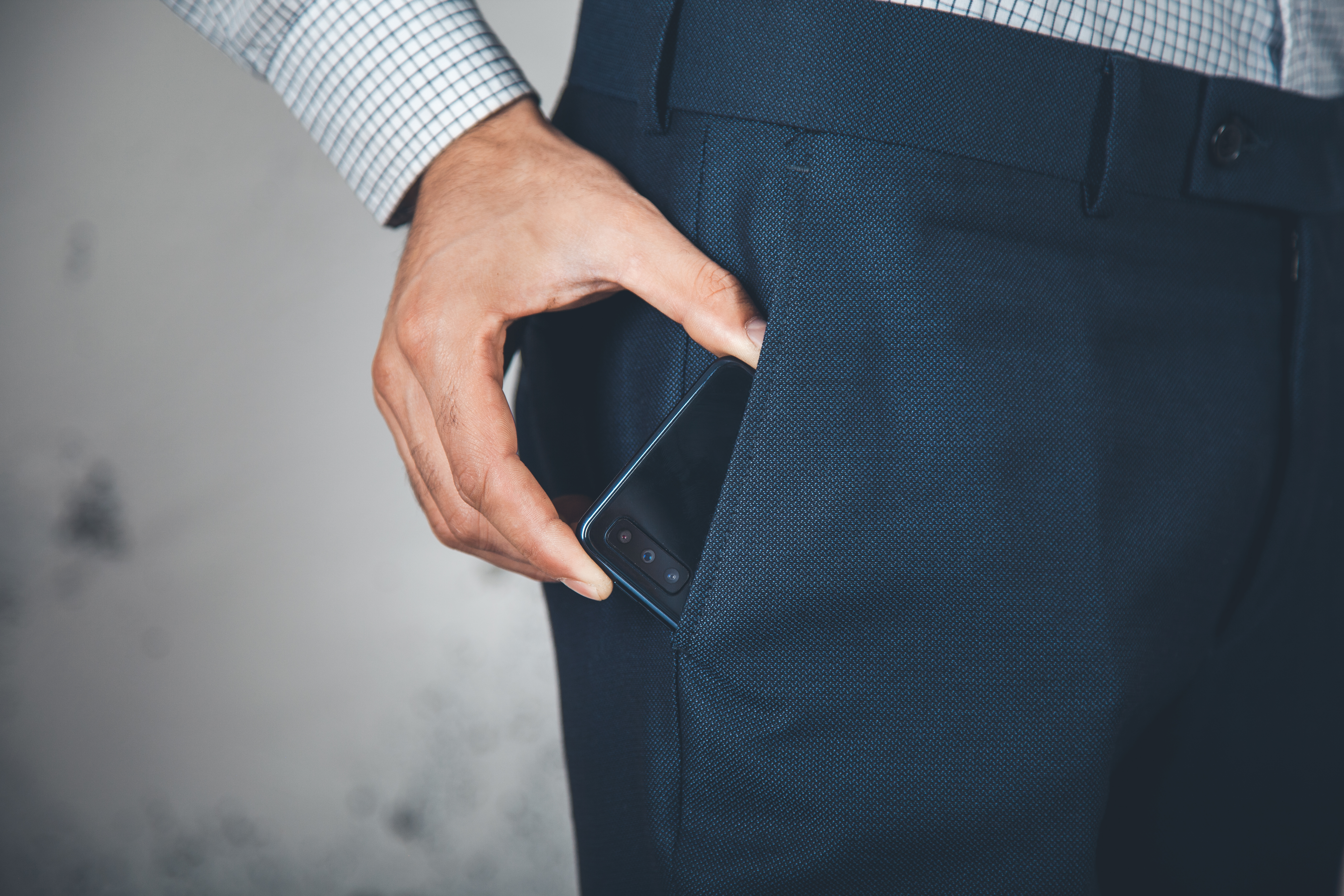 Hombre mano teléfono sobre poket sobre fondo abstracto. | Fuente: Shutterstock