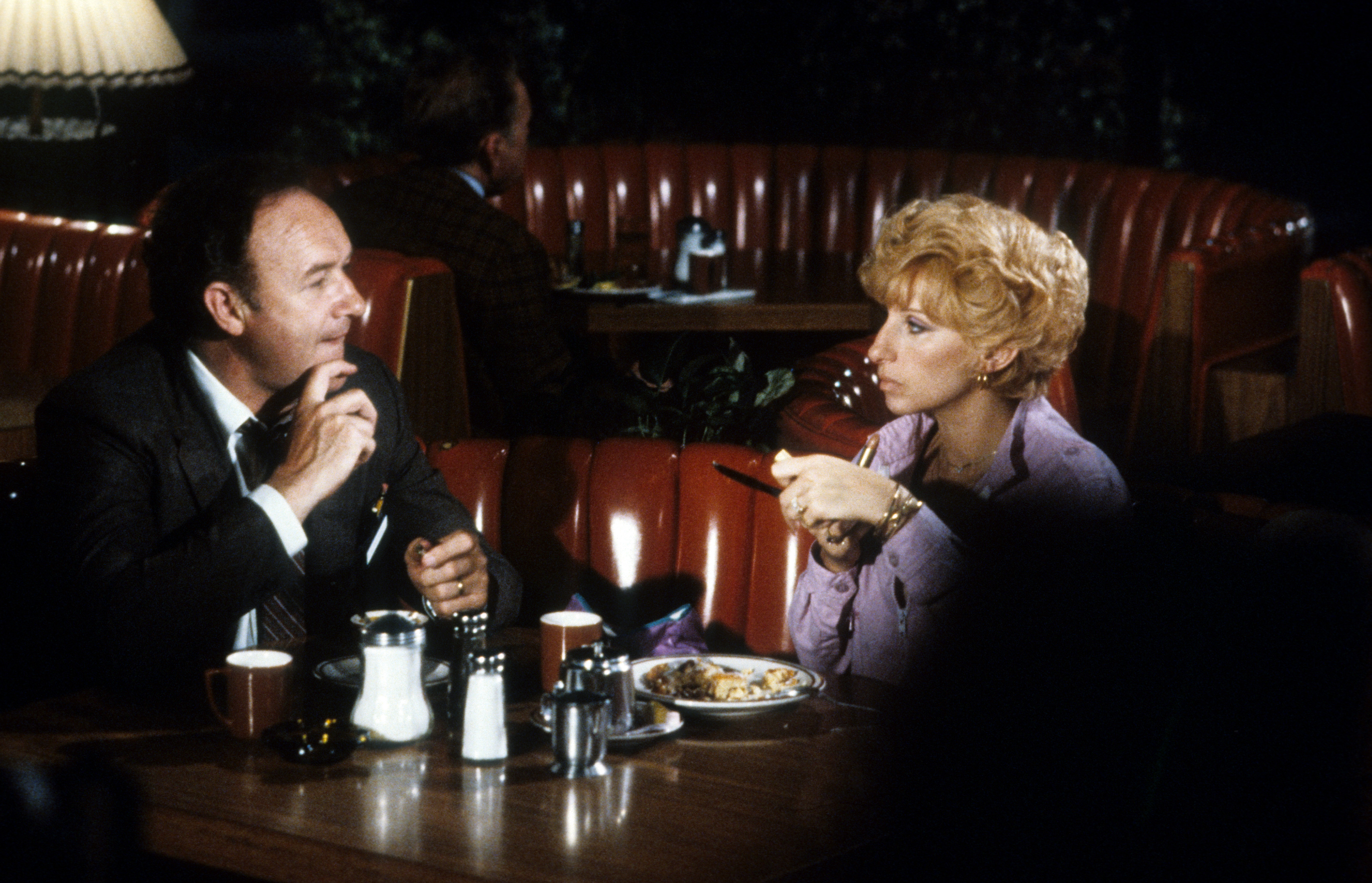 Gene Hackman y Barbra Streisand están sentados en una cabina cenando juntos en una escena de la película de 1981 "All Night Long". | Fuente: Getty Images