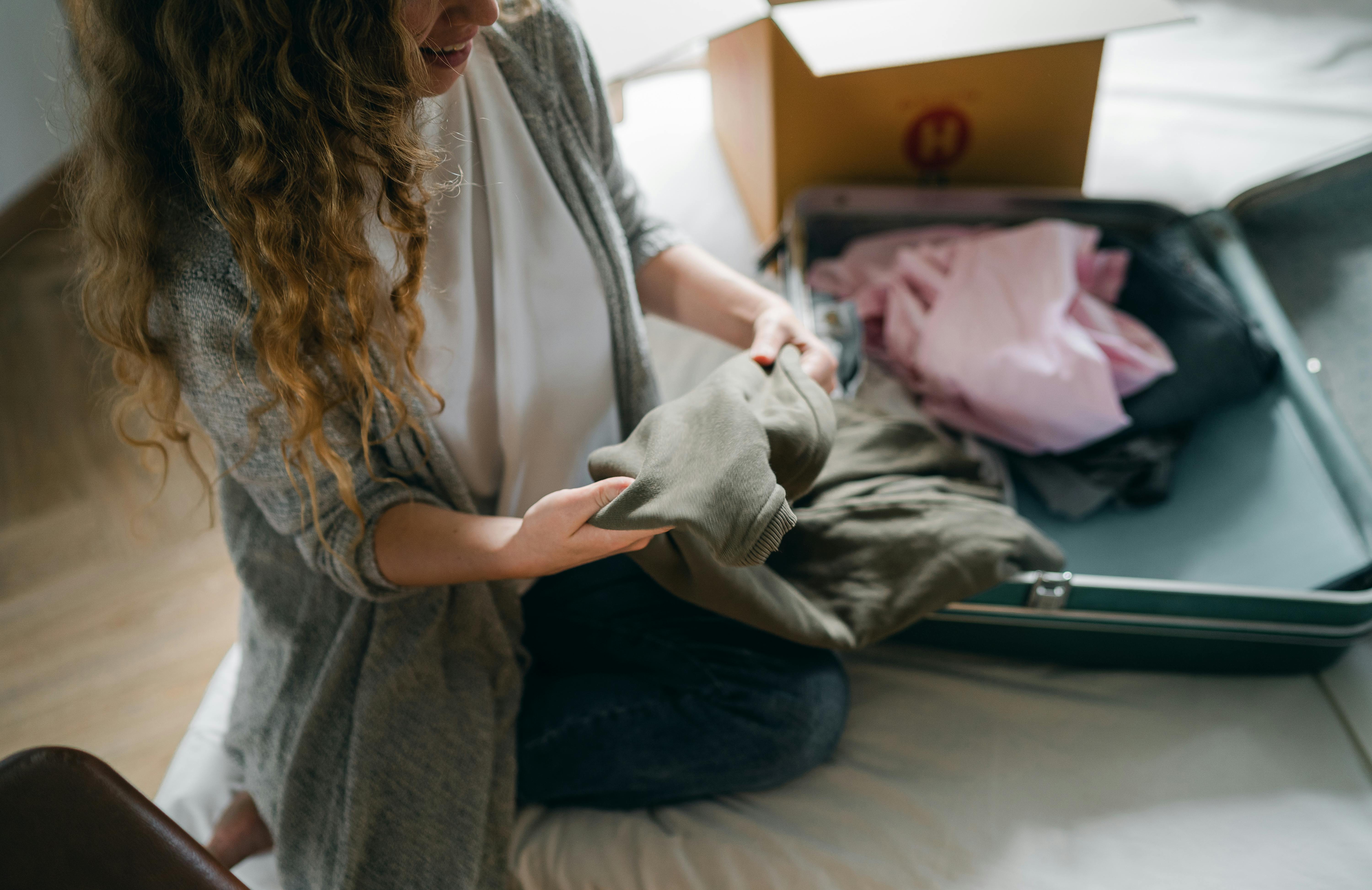 Una donna che mette i vestiti in una borsa | Fonte: Pexels