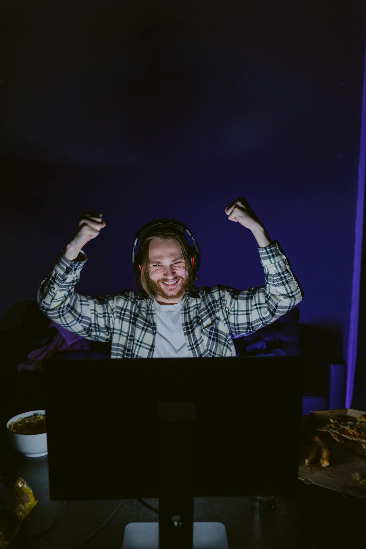 Un hombre usando auriculares mientras se ríe de la pantalla | Fuente: Pexels