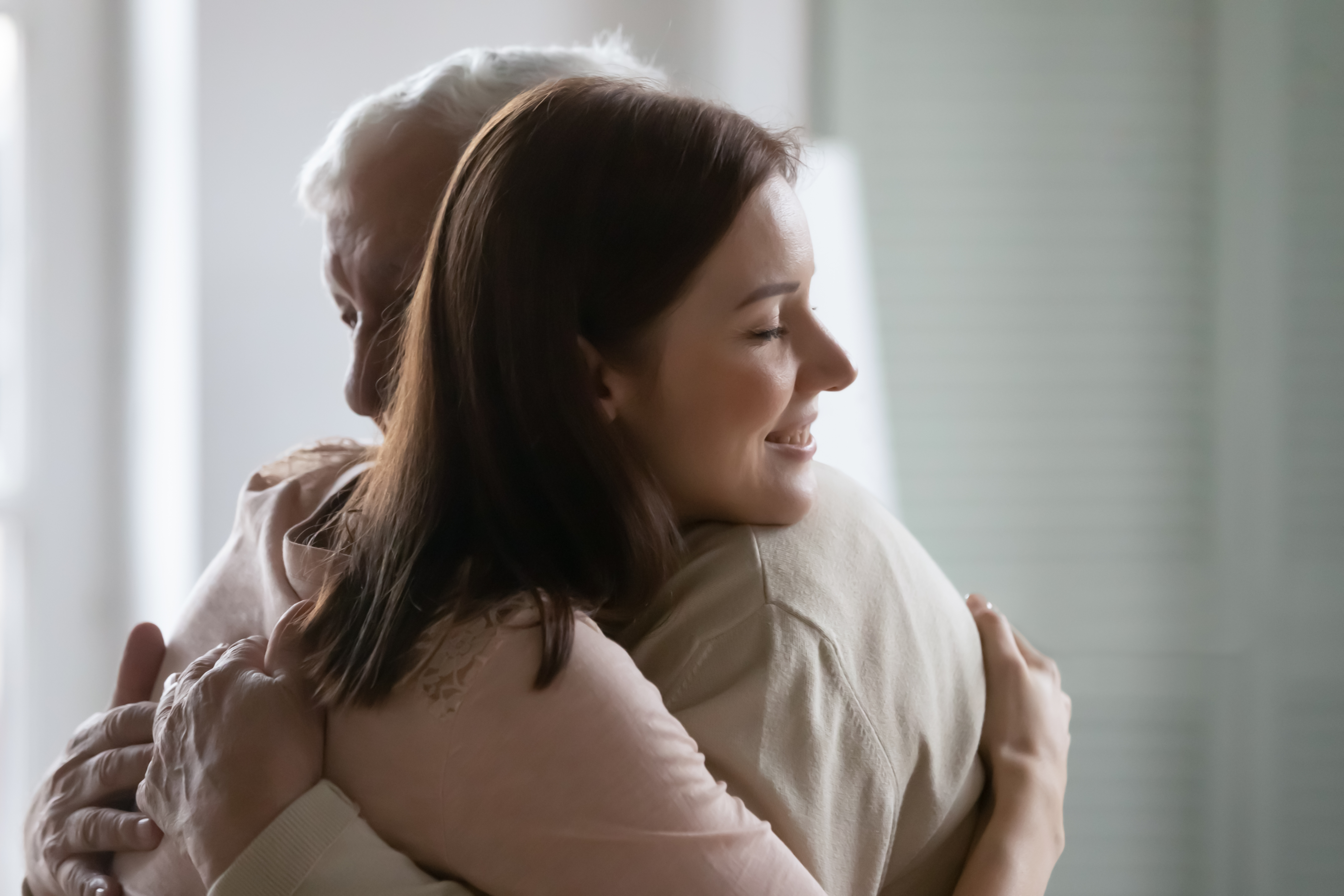 Primer plano de una bella mujer joven sonriendo abrazando a un hombre mayor | Fuente: Shutterstock.com