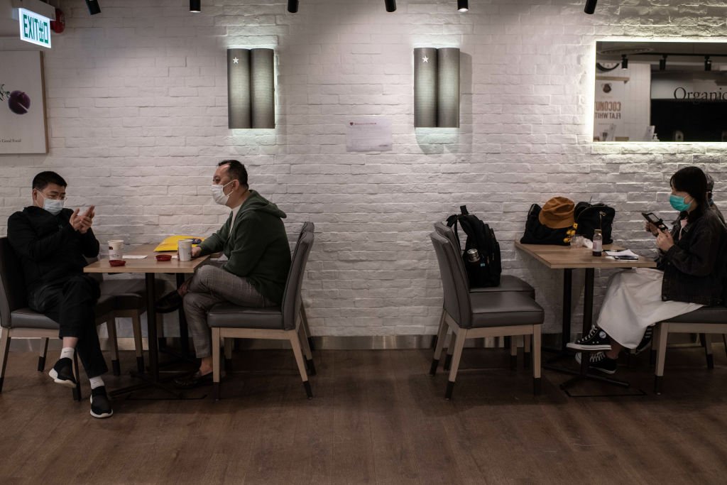 Clientes en Hong Kong con máscaras quirúrgicas se sientan respetando las medidas de distancia social en un café. I Foto: Getty Images
