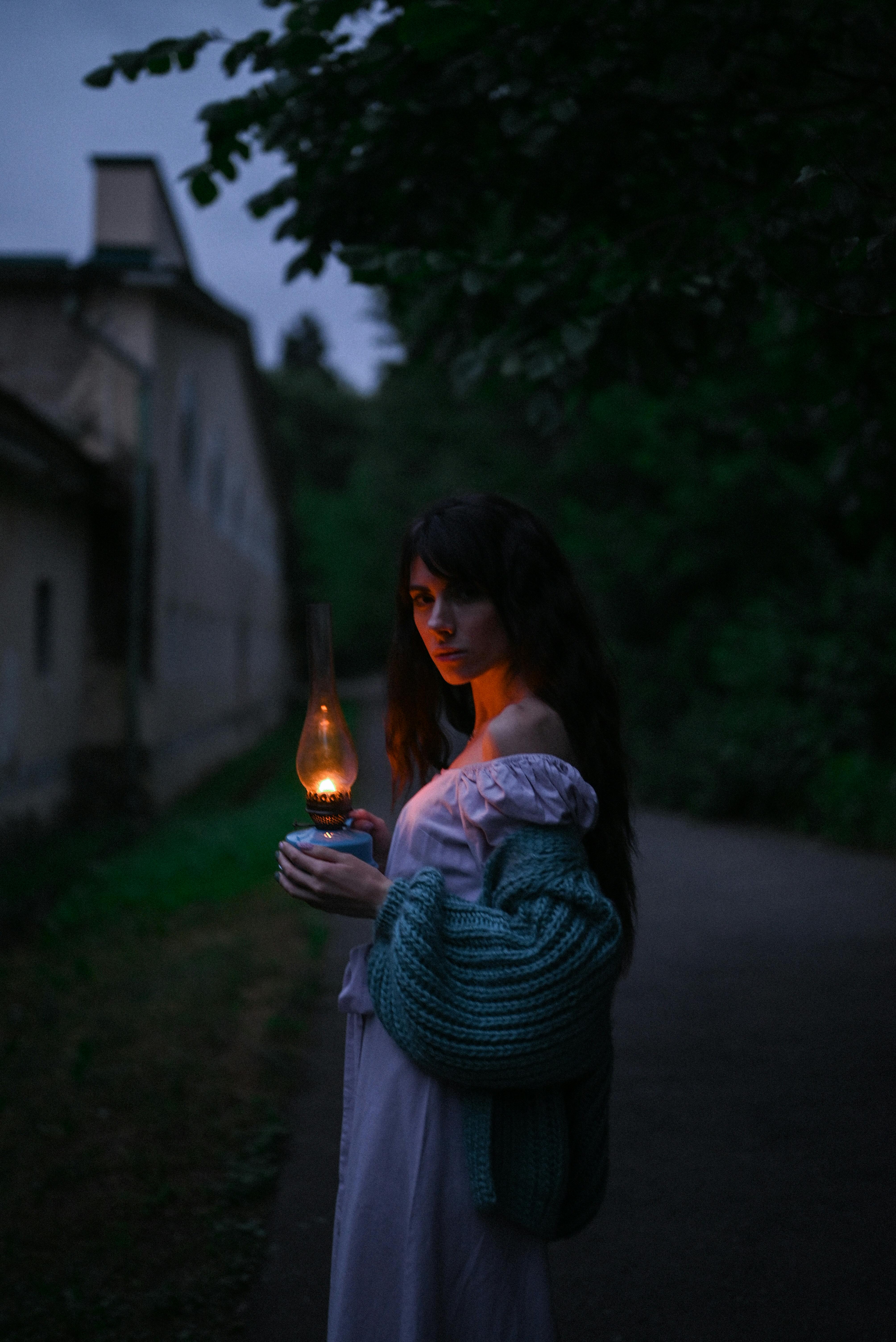 Mujer con una vieja lámpara de queroseno en la oscuridad | Fuente: Pexels