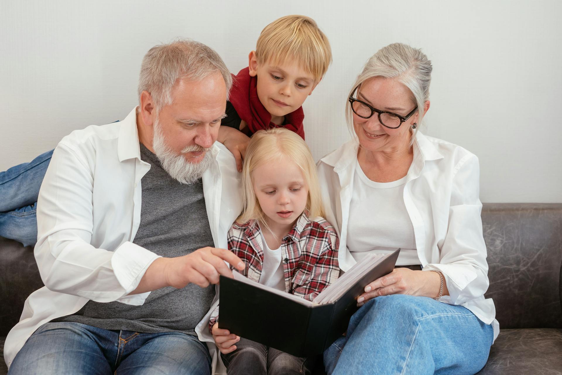 Abuelos mirando un álbum de fotos con sus nietos | Fuente: Pexels