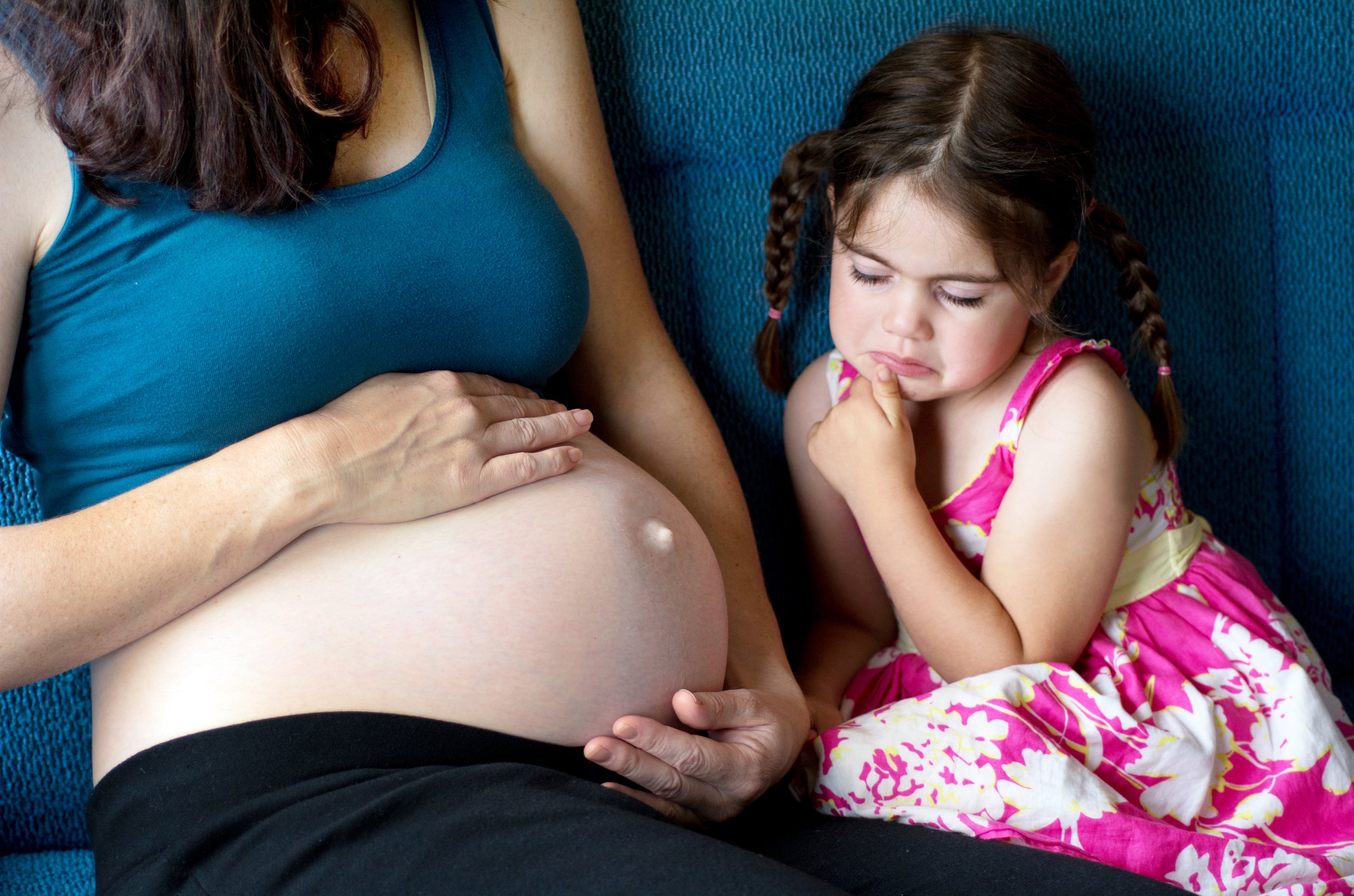 Niña mira celosa barriga de mamá embarazada. | Foto: Shutterstock