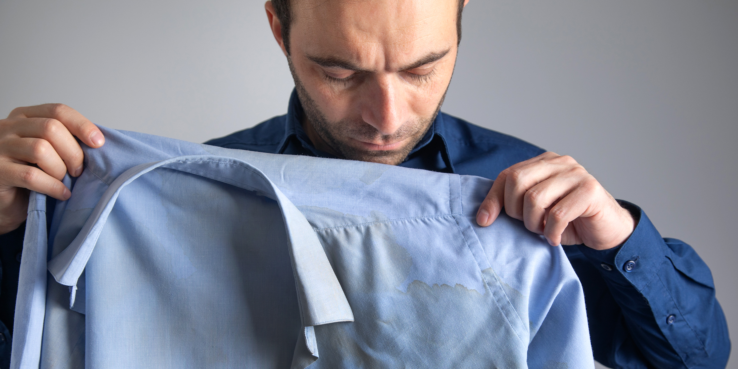 Un hombre sujetando una camisa manchada | Fuente: Shutterstock