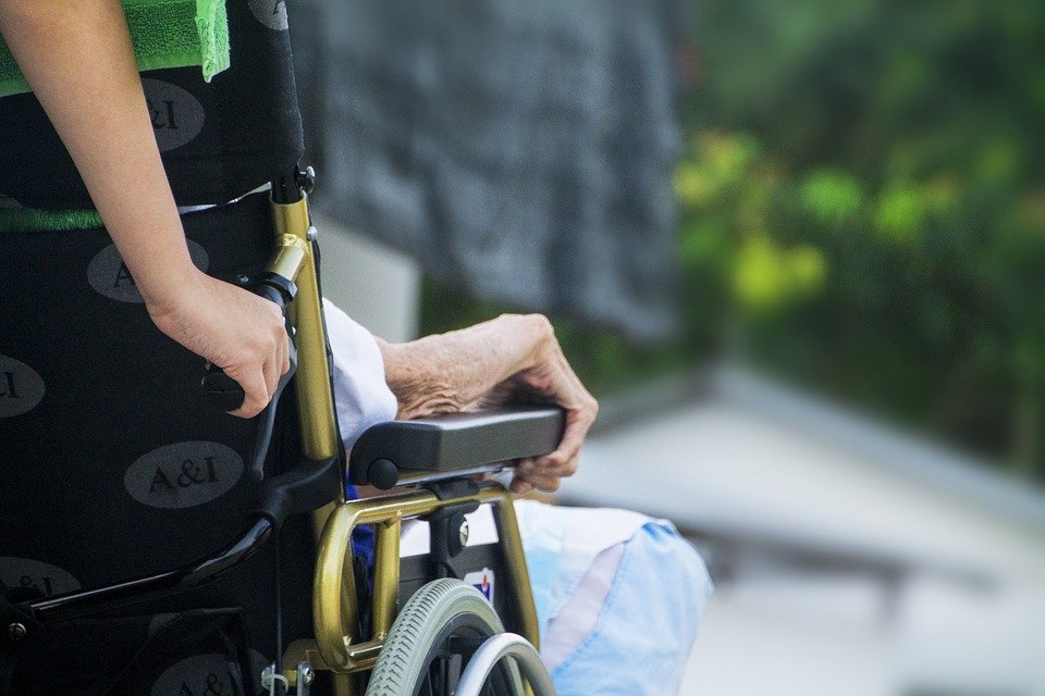 Anciana en silla de ruedas siendo acompañada. │Foto: Pixabay