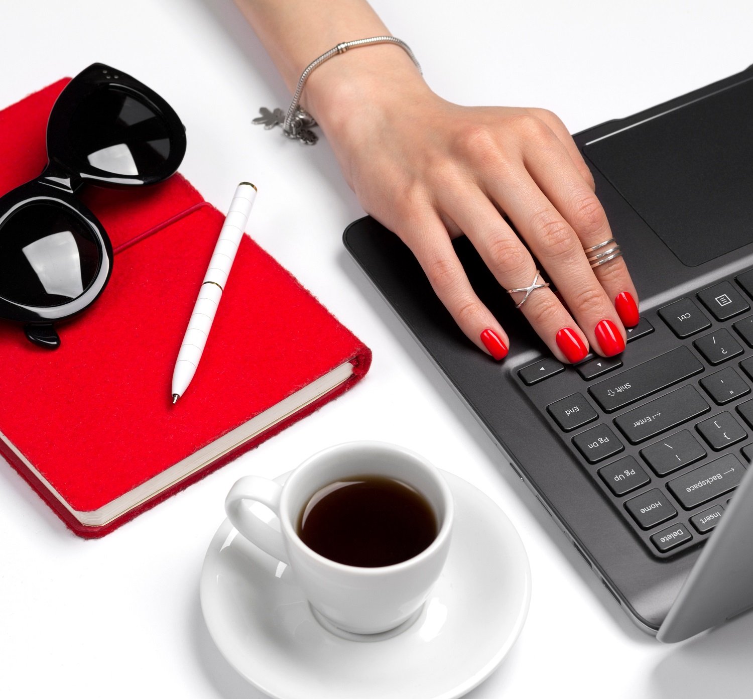 Mujer usando una computadora portátil luciendo un esmalte de uñas rojo. | Foto: Shutterstock