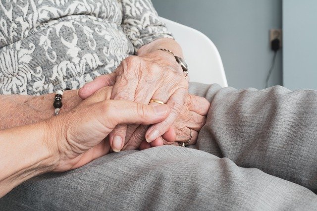 Hombre joven toma la mano de una mujer anciana. | Foto: Pixabay