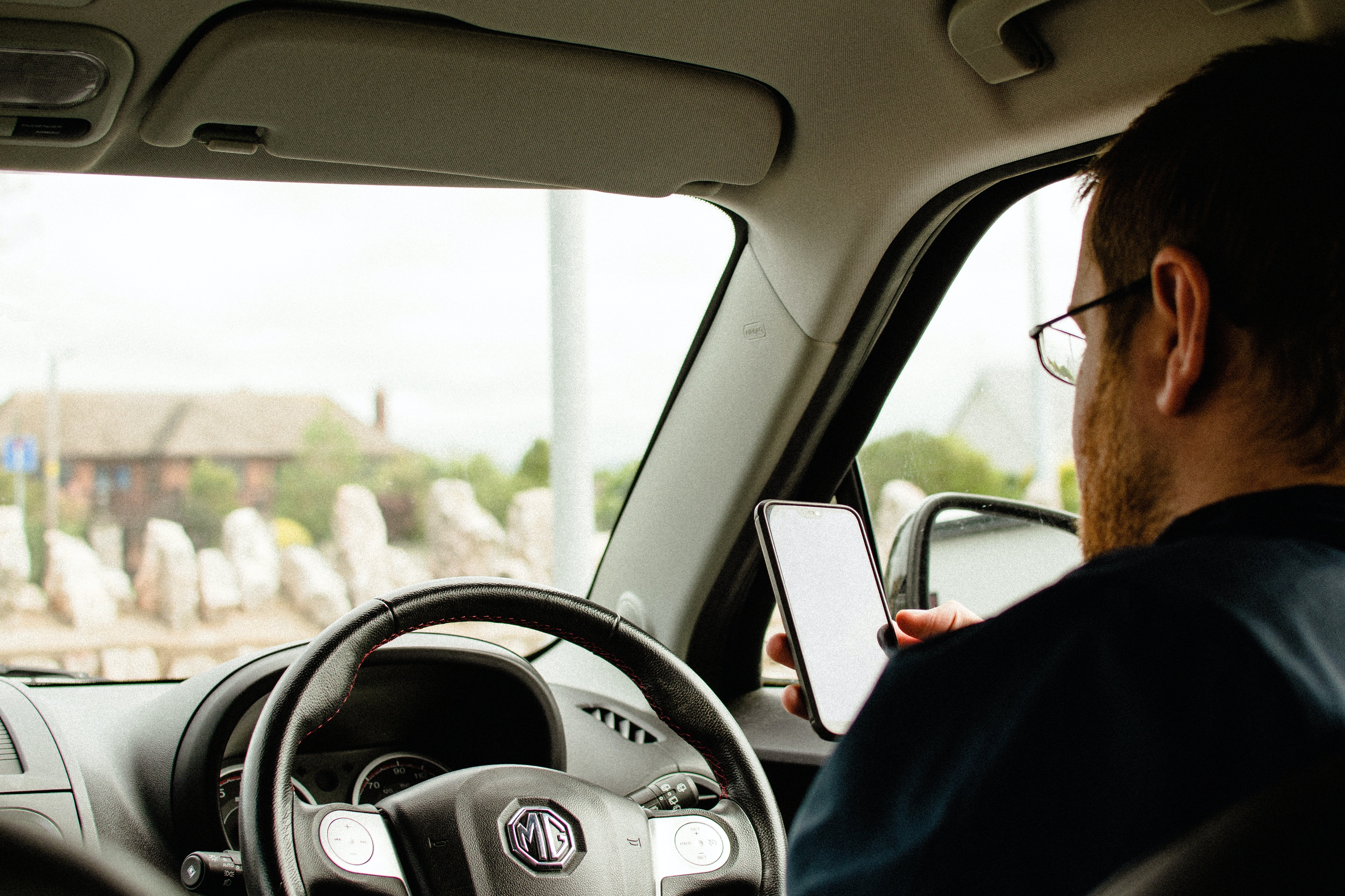 Un hombre revisa un teléfono celular en el interior de un vehículo. | Foto: Pexels