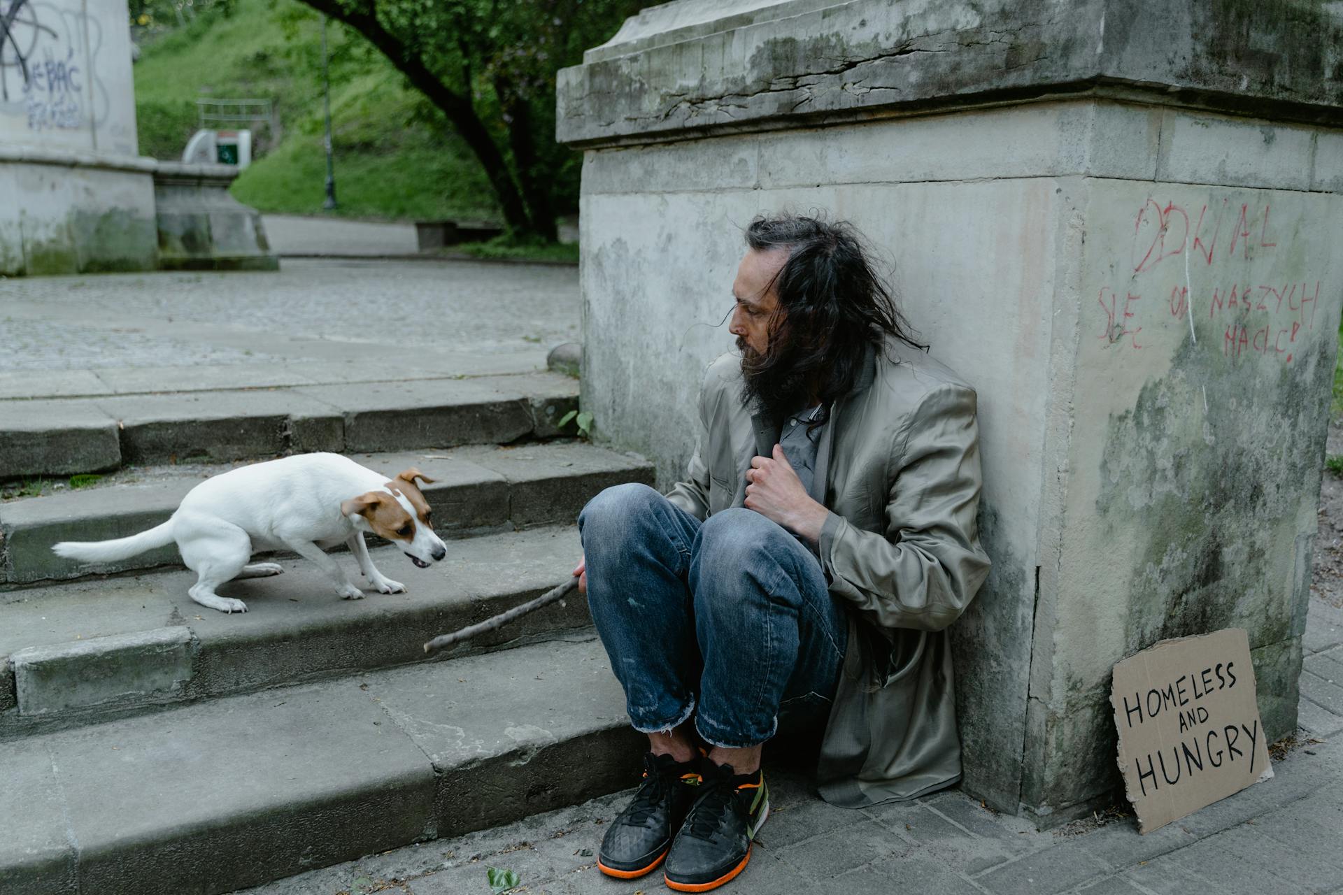 Un vagabundo sentado con un perro | Fuente: Pexels