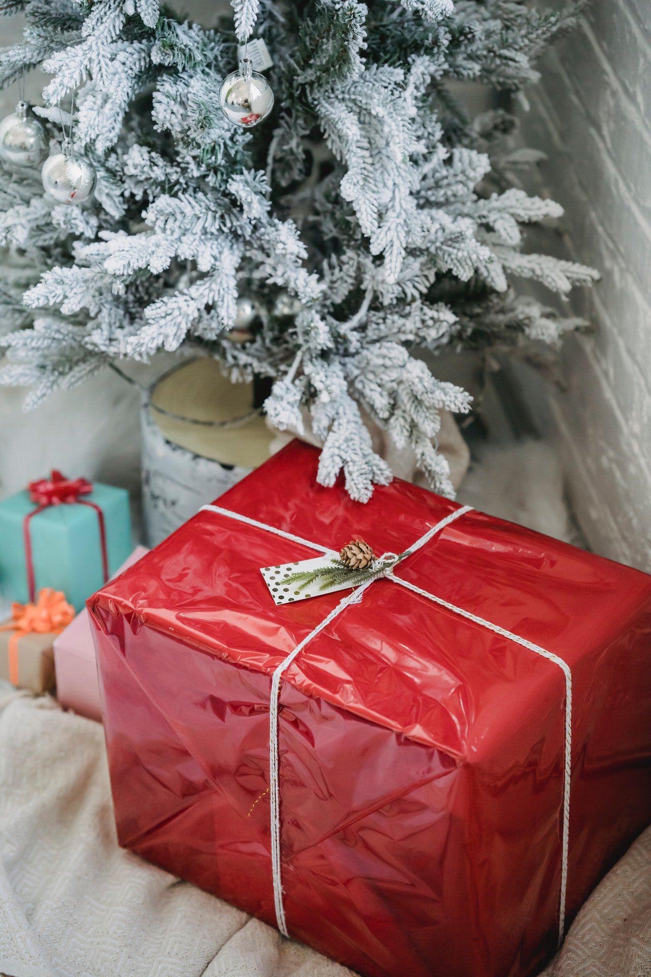 Un regalo envuelto en papel rojo, debajo del árbol de Navidad. | Foto: Pexels