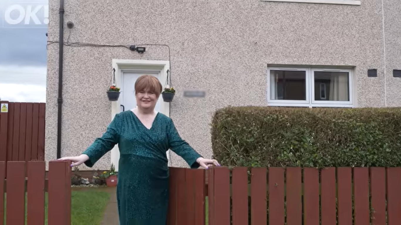 Susan Boyle fotografiada frente a la casa de su infancia en Blackburn, Escocia | Fuente: YouTube/OK!MagazineUK