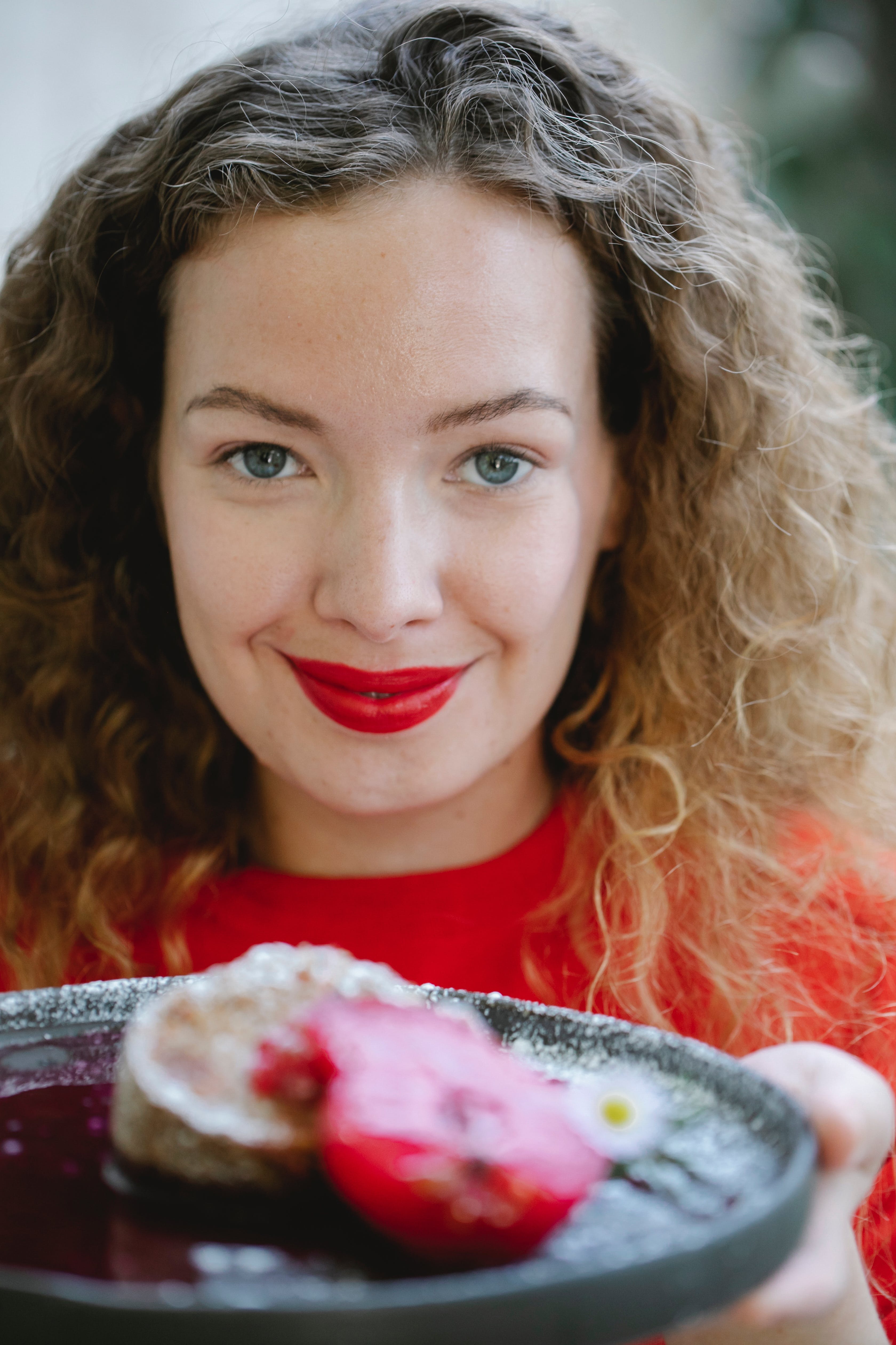 Una mujer con un plato de tarta dulce en la mano. | Fuente: Pexels