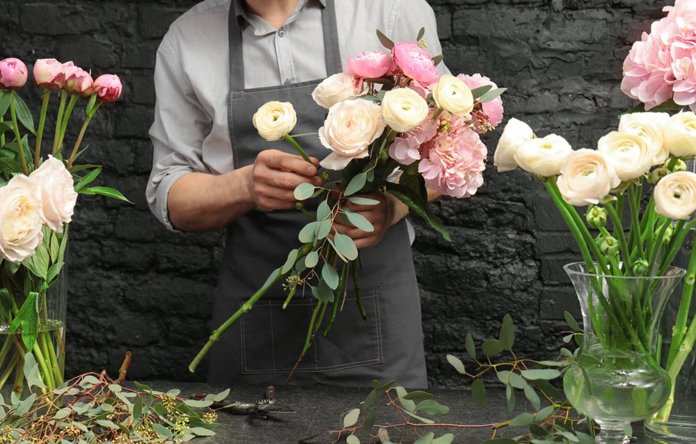 Hombre en floristería creando hermoso ramo en florería, primer plano. | Fuente: Shutterstock
