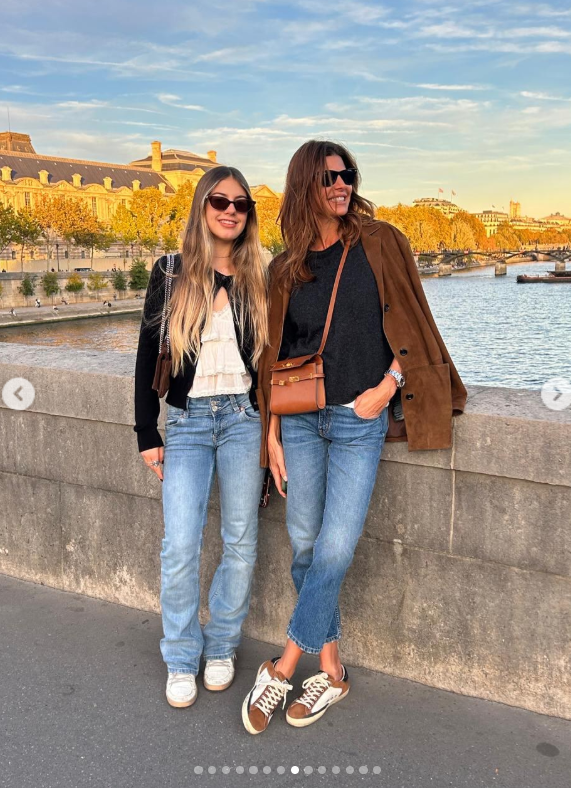 Antonia Macri y su madre Juliana Awada posan sonrientes a orillas del río Sena con la arquitectura parisina de fondo, combinando jeans claros con prendas otoñales en tonos tierra, lentes oscuros y zapatillas urbanas. | Fuente: Instagram/juliana.awada