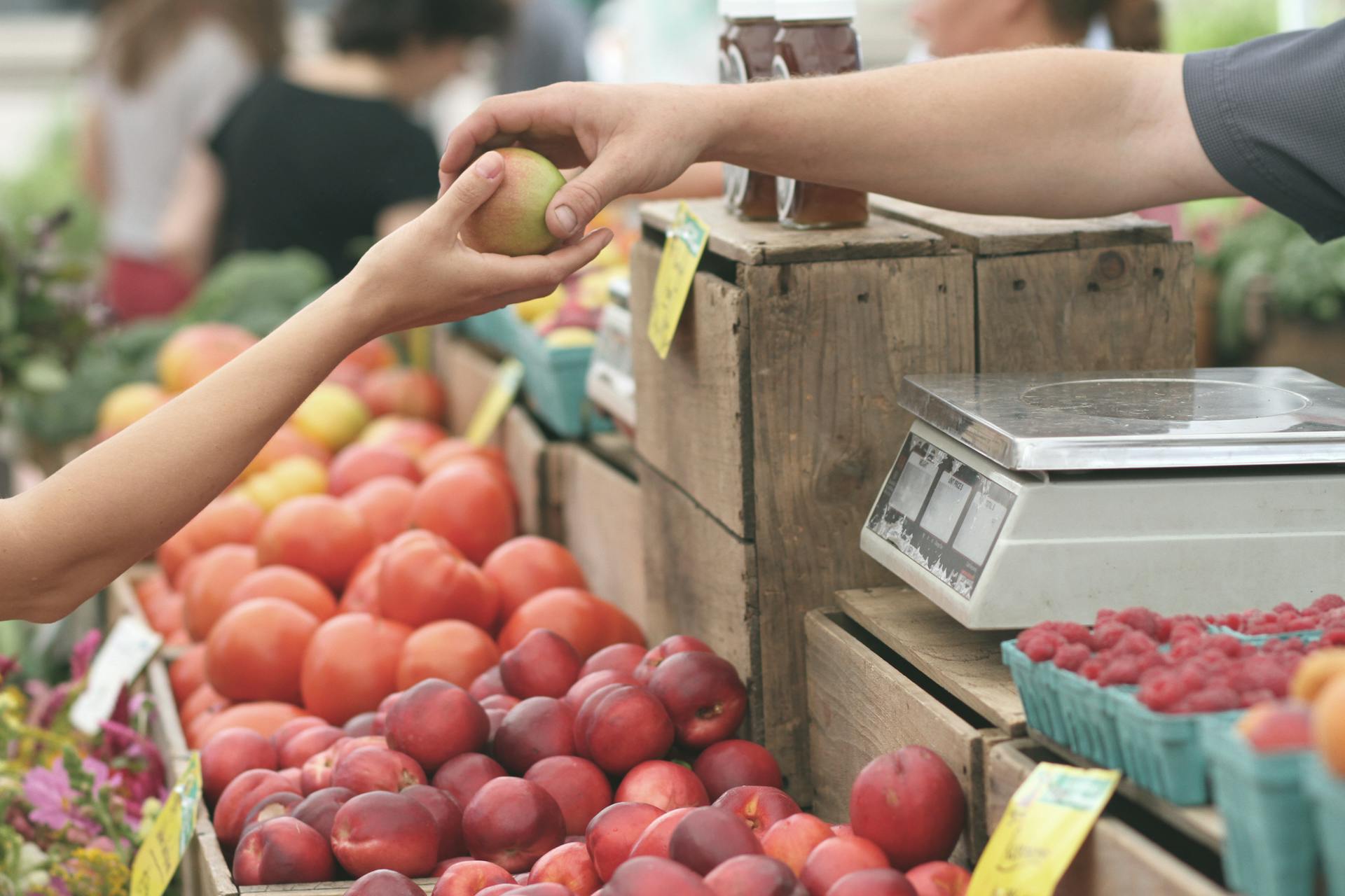 Primer plano de una persona entregando una fruta a otra | Fuente: Pexels