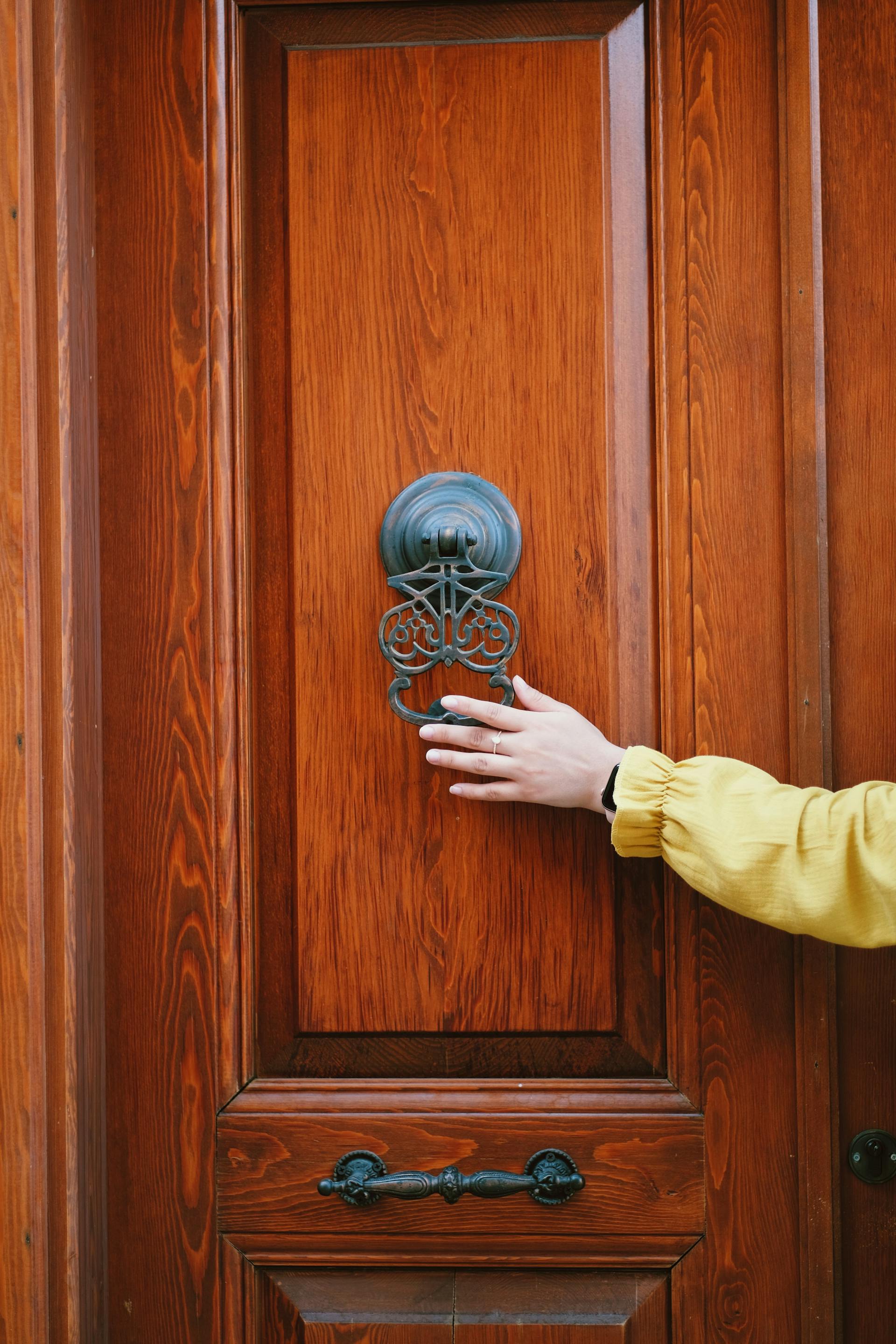 Un'inquadratura a distanza di una persona che tiene in mano un batacchio per la porta | Fonte: Pexels