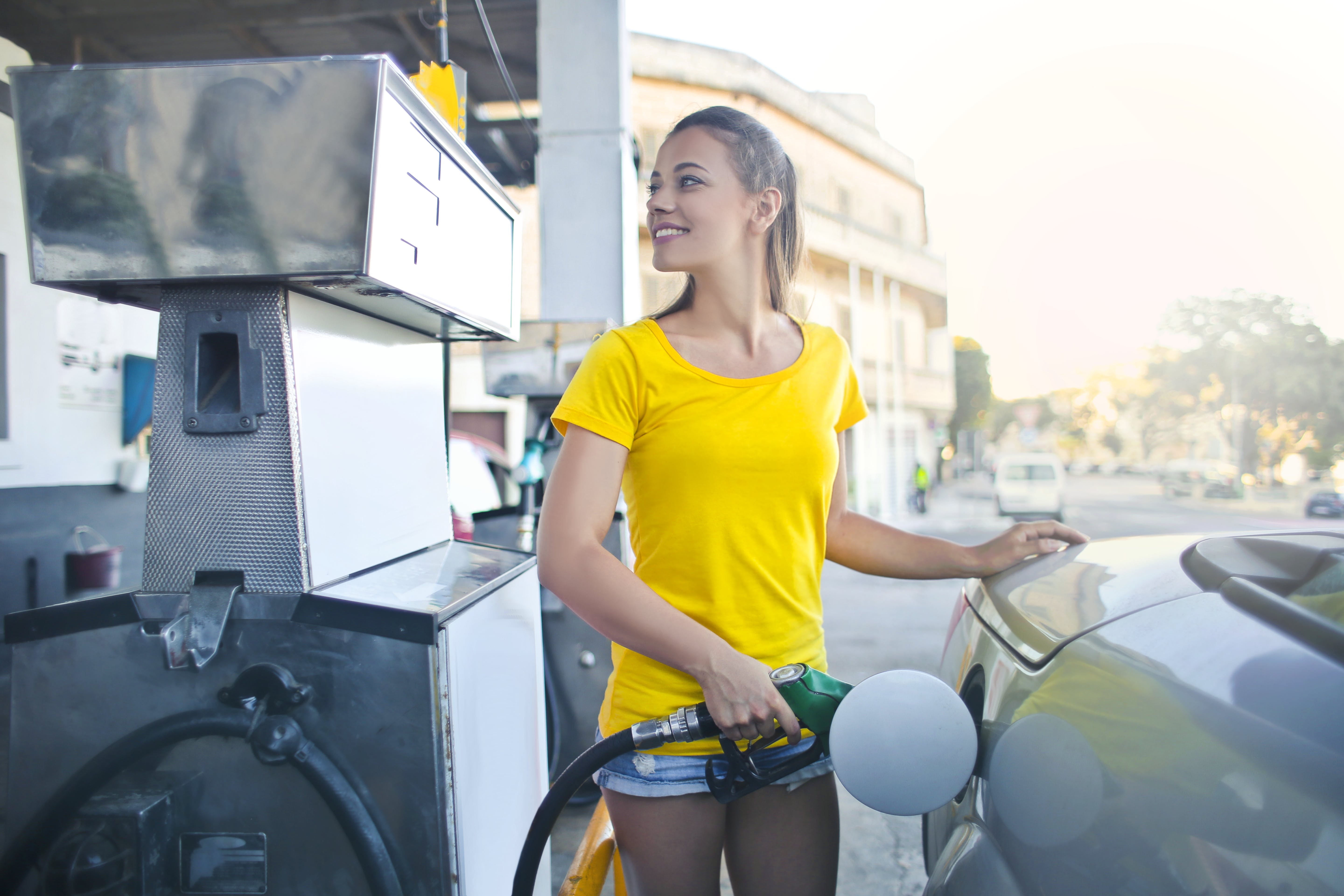 Una mujer con un top amarillo repostando su Automóvil. | Fuente: Pexels